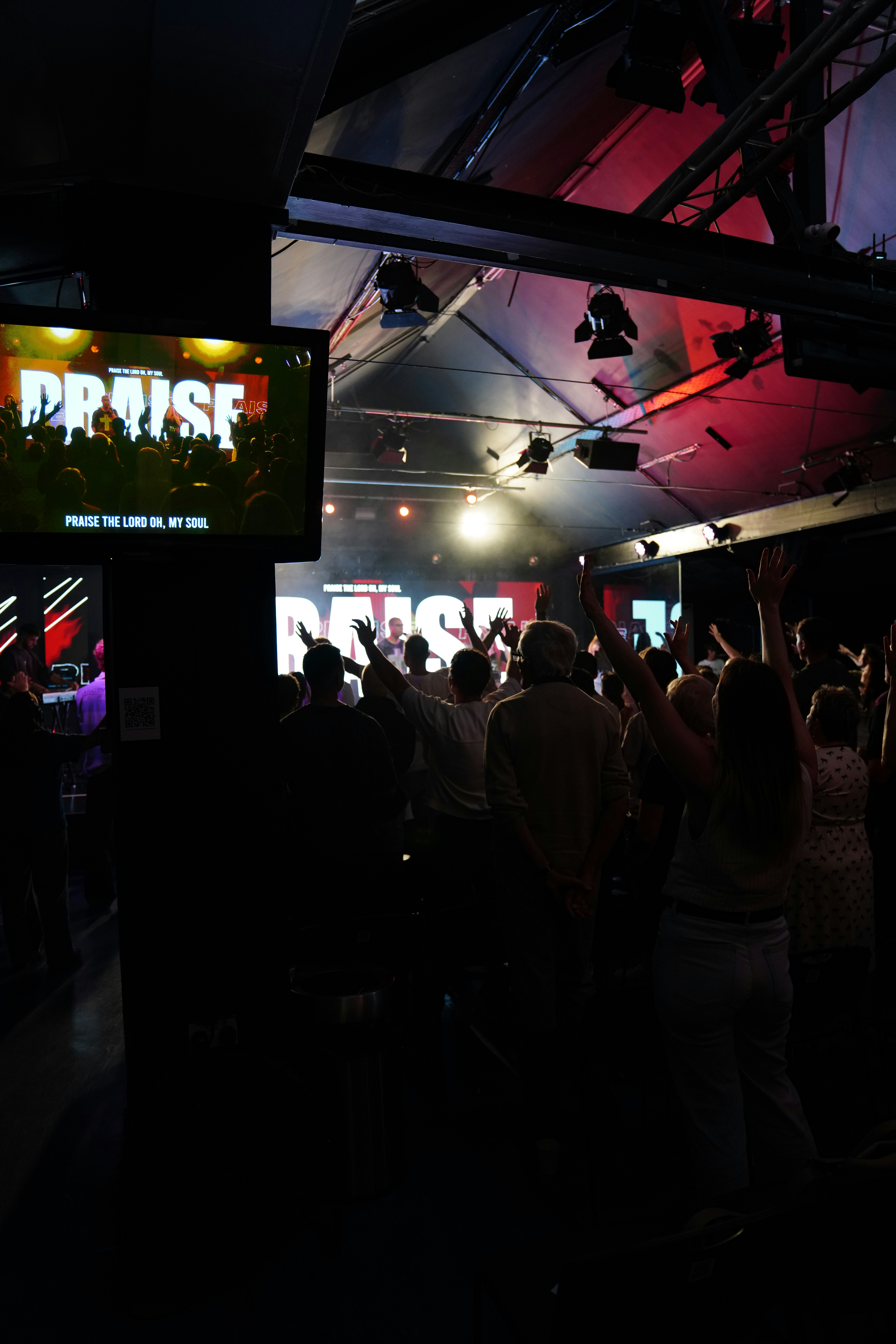 People with hands raised in a concert hall