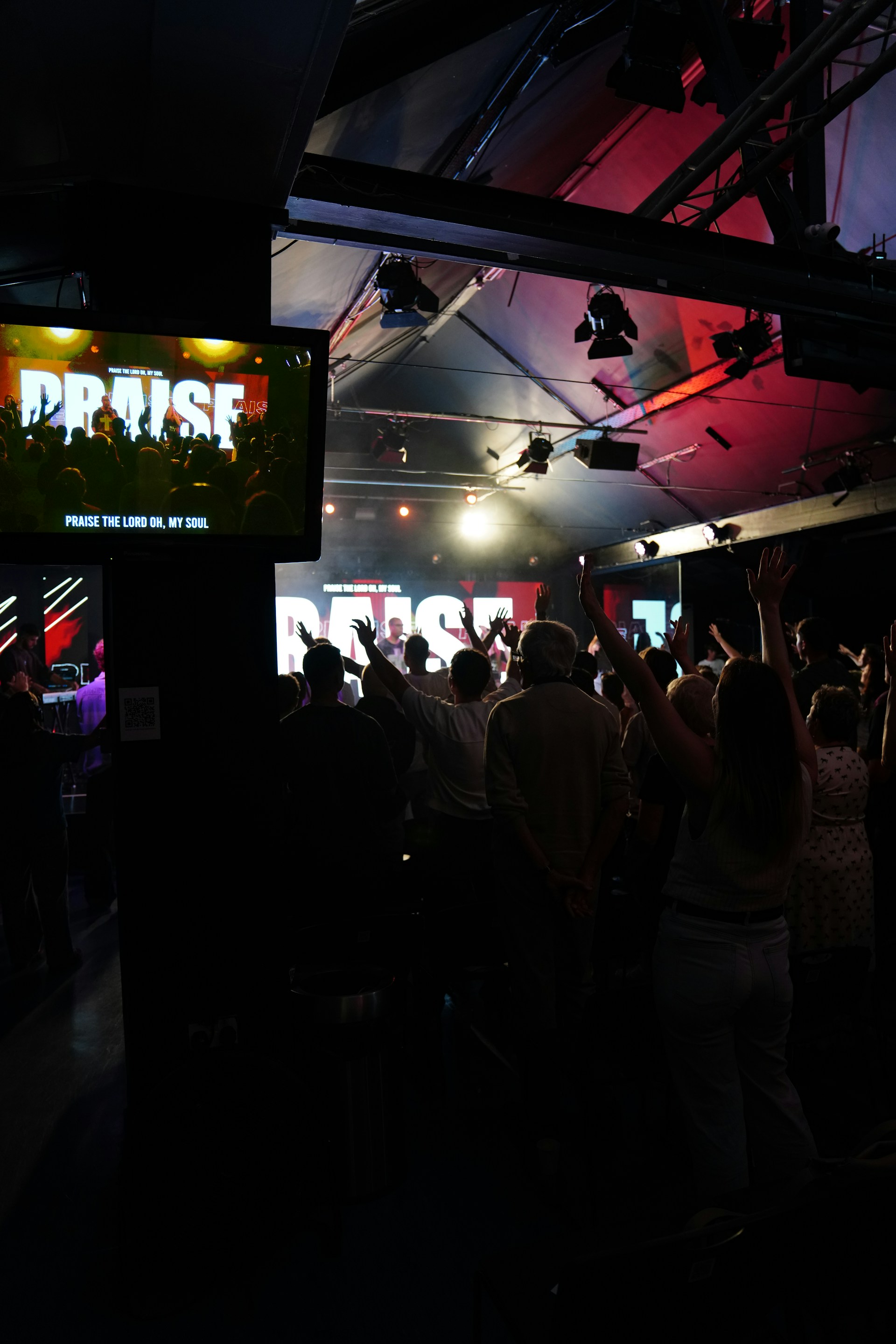 People with hands raised in a concert hall