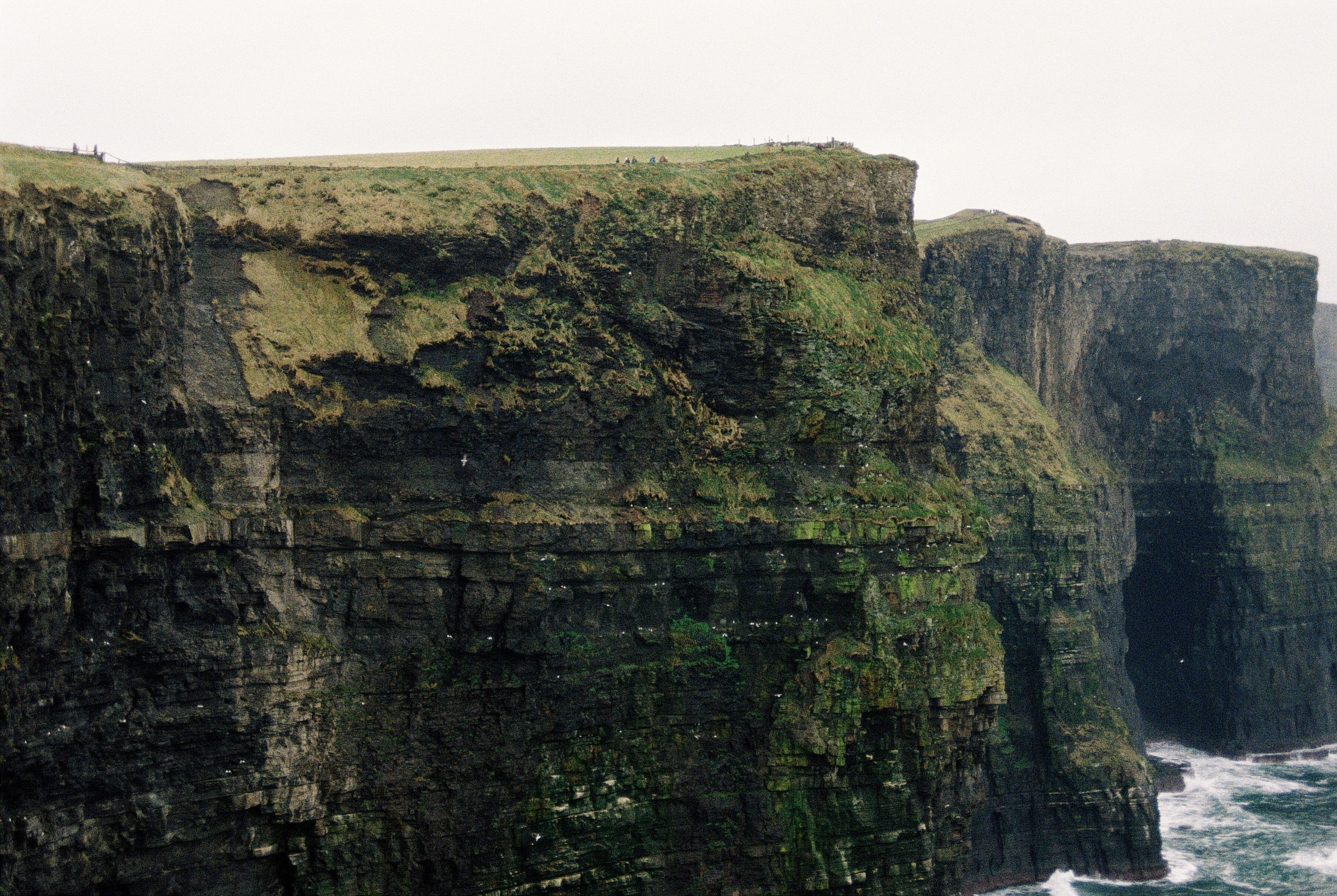 Dramatic cliffs meet the ocean on a cloudy day.