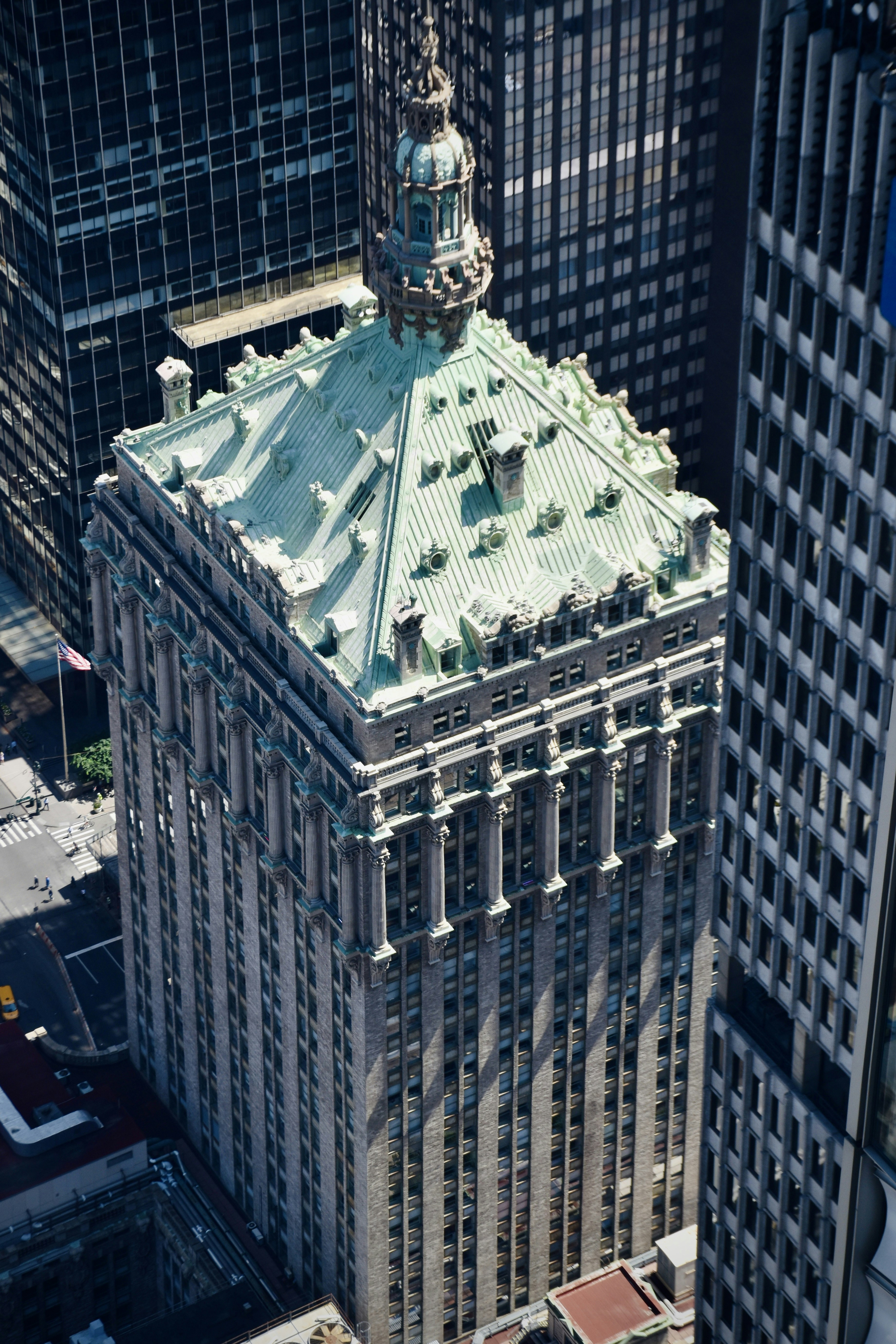 A tall glass and copper-roofed high-rise tower rising above a dense city skyline