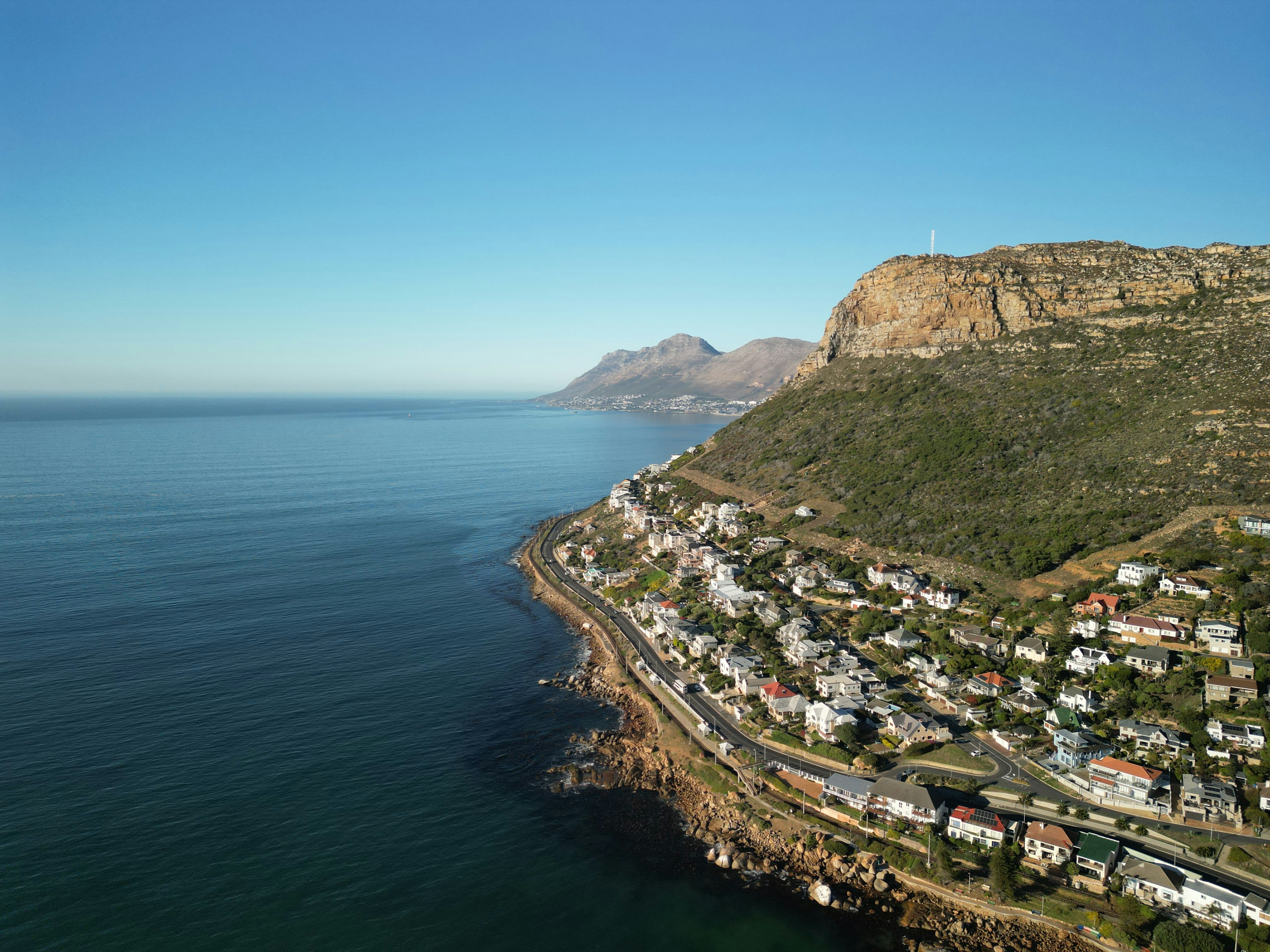 Coastal town nestled against a mountain beside the ocean.