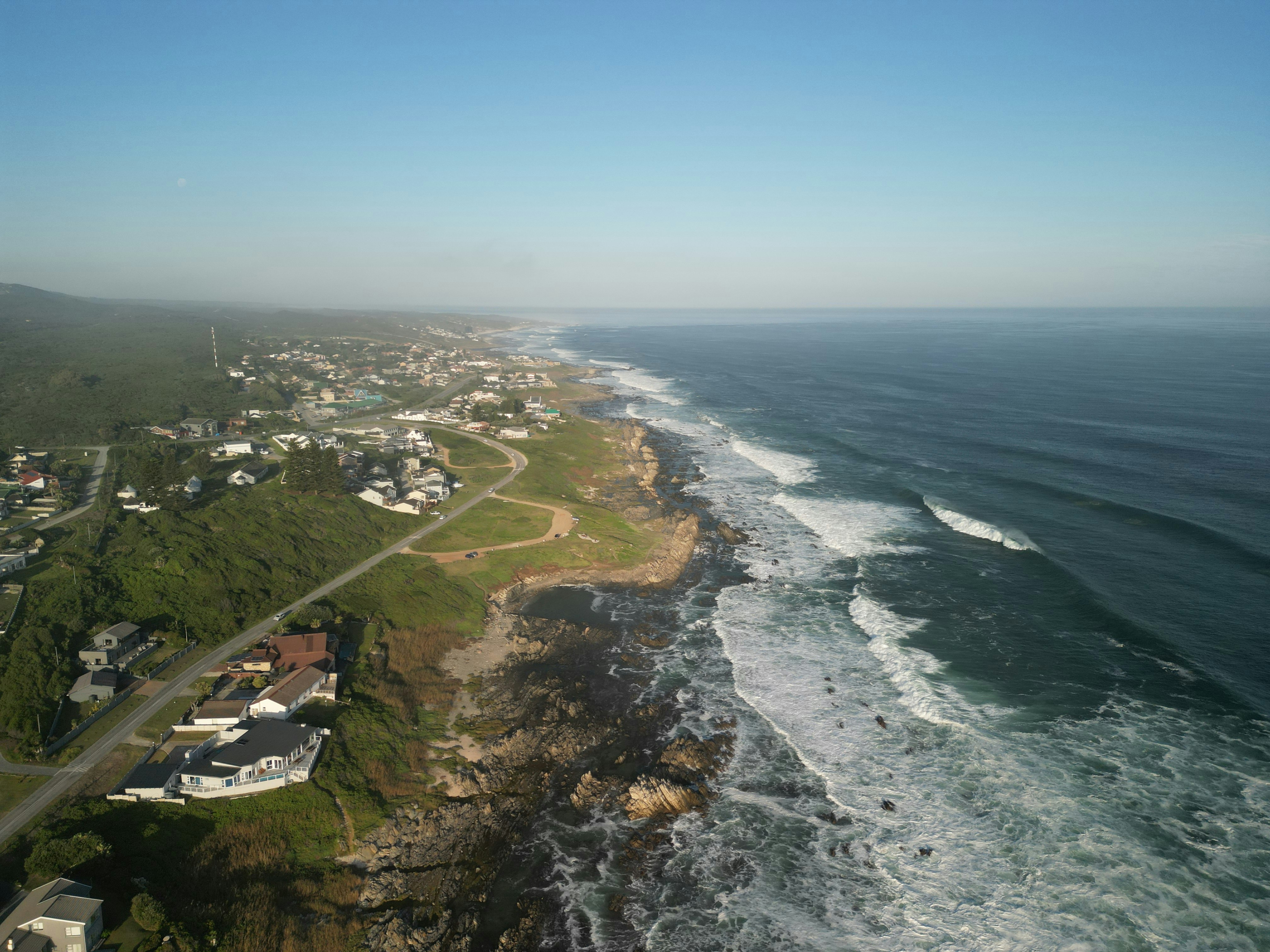Aerial view of a coastal town with waves crashing ashore.