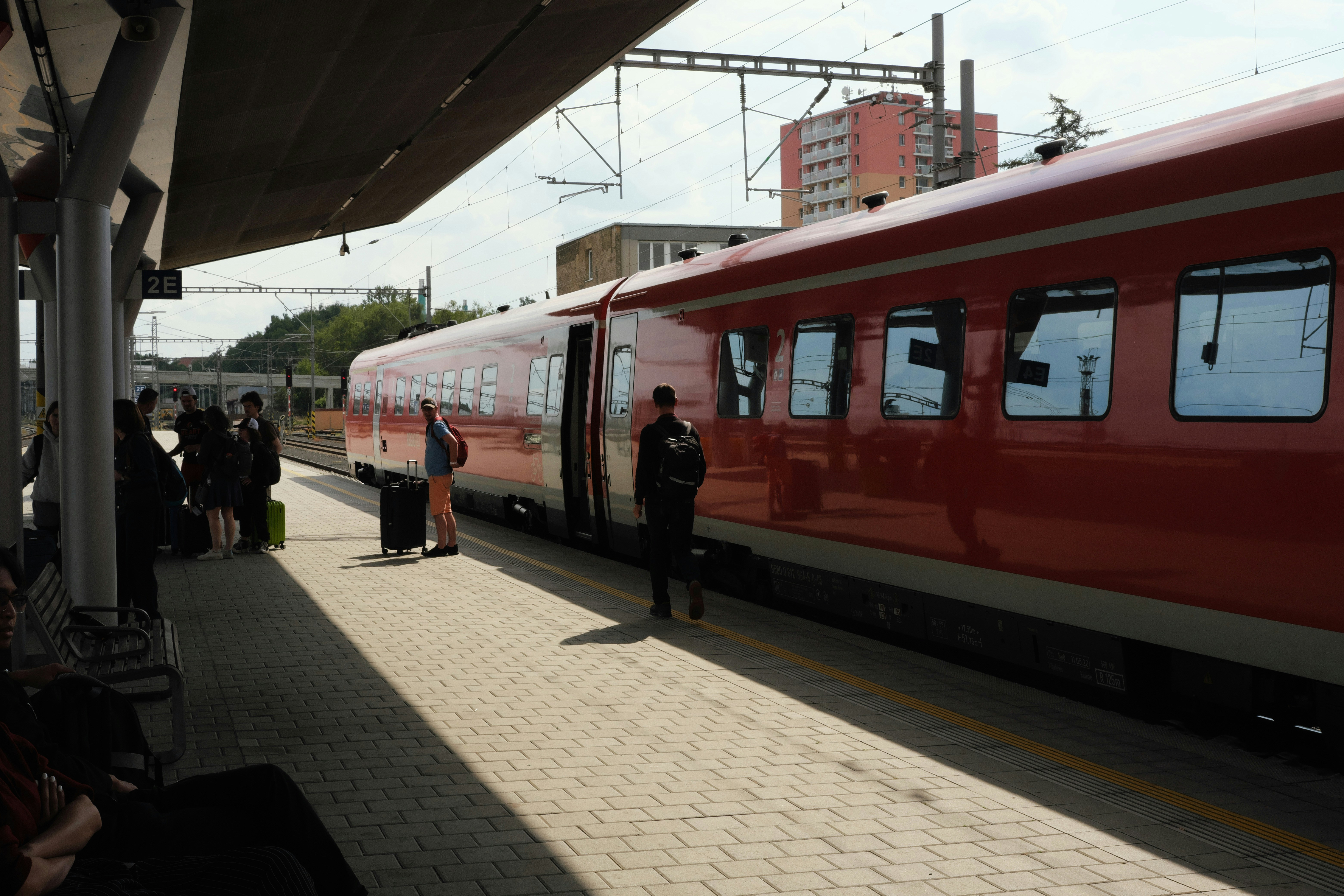 Red train at a station platform with people