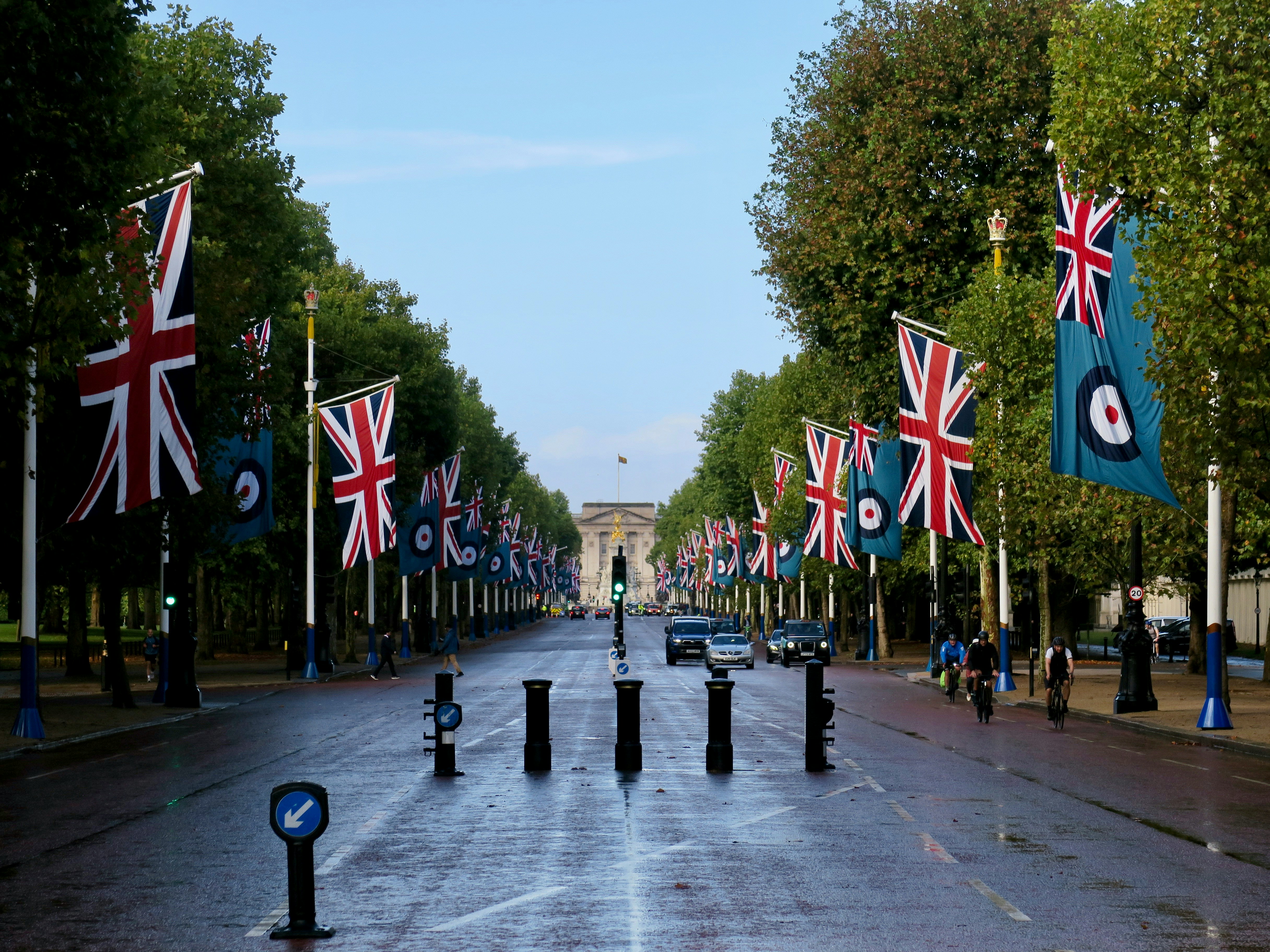 Union jack flags line a wide street leading to an arch.