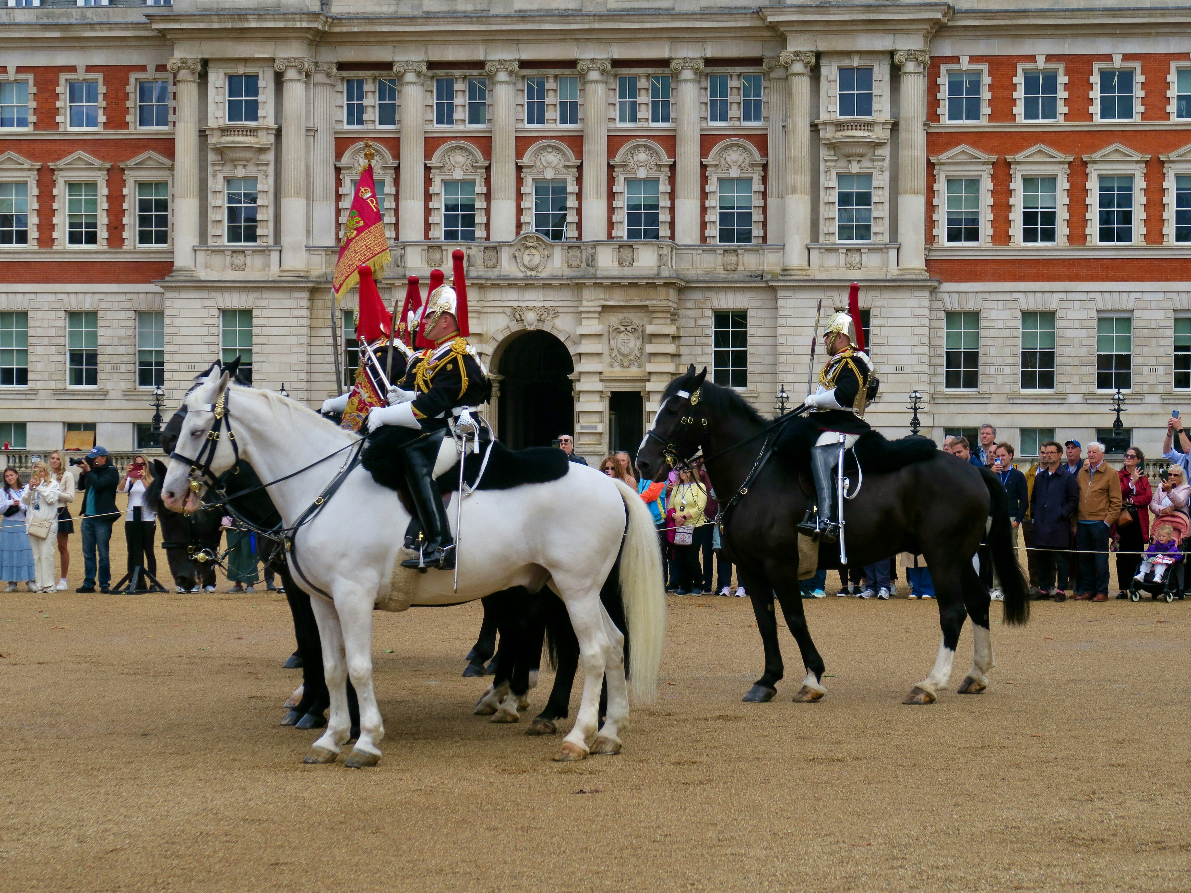 Soldiers on horseback in front of a grand building.