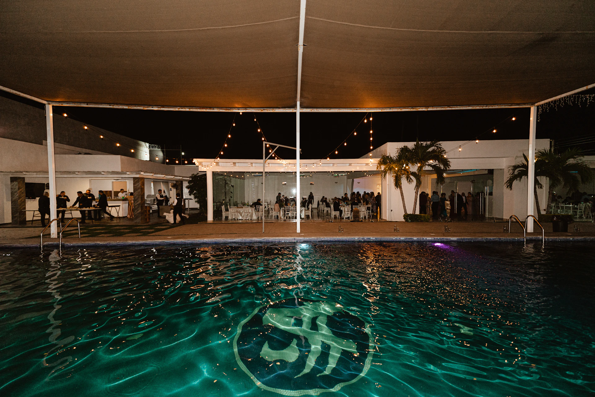 Poolside event venue with string lights at night.