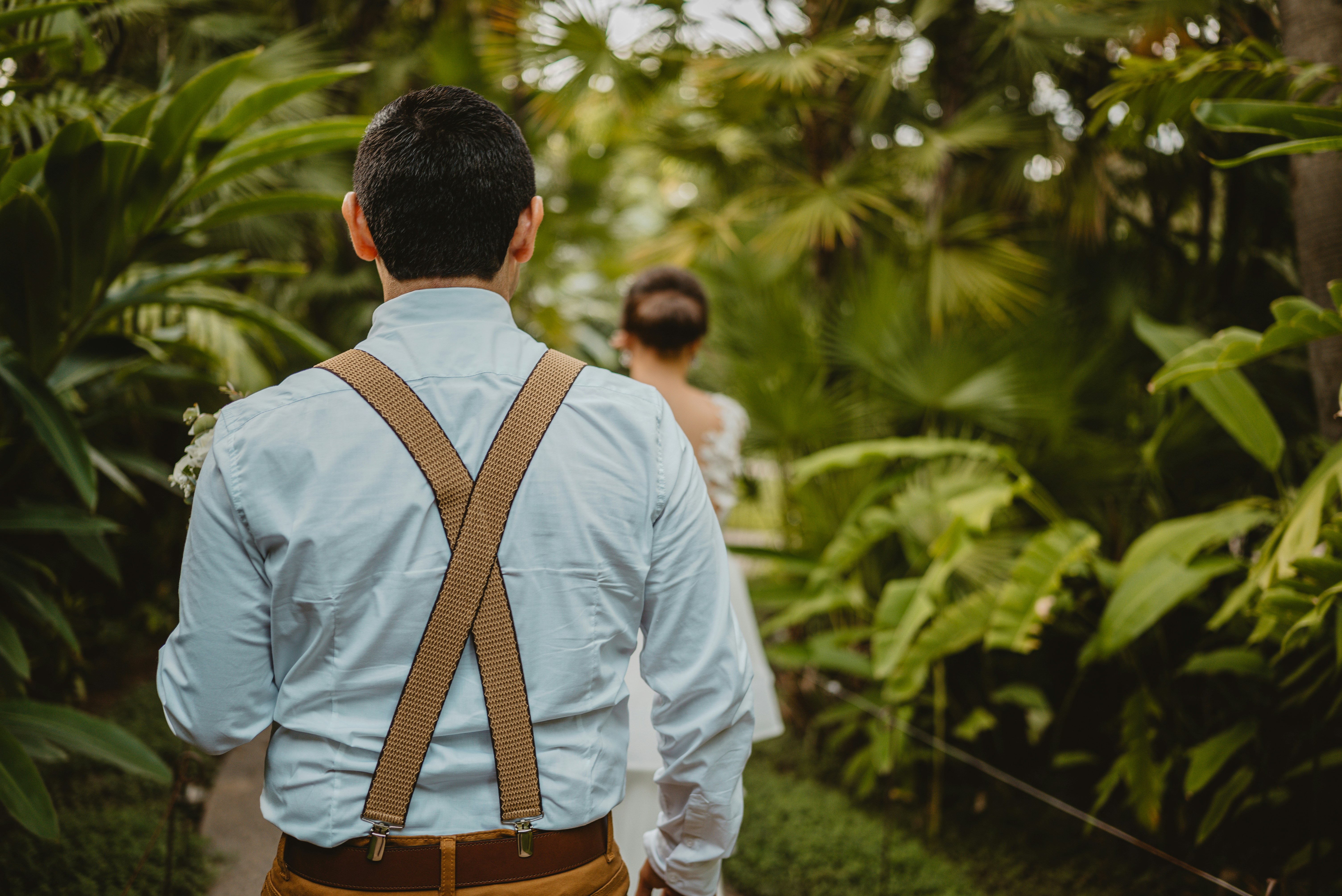Man in suspenders walks towards woman in garden
