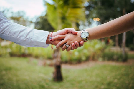 Two people shaking hands outdoors with a blurred background