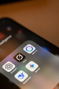 Smartphone screen displays ai app icons: chatgpt, grok, meta ai, gemini