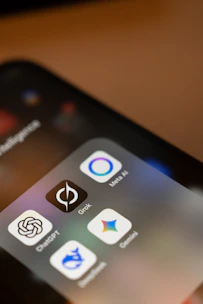 Smartphone screen displays ai app icons: chatgpt, grok, meta ai, gemini