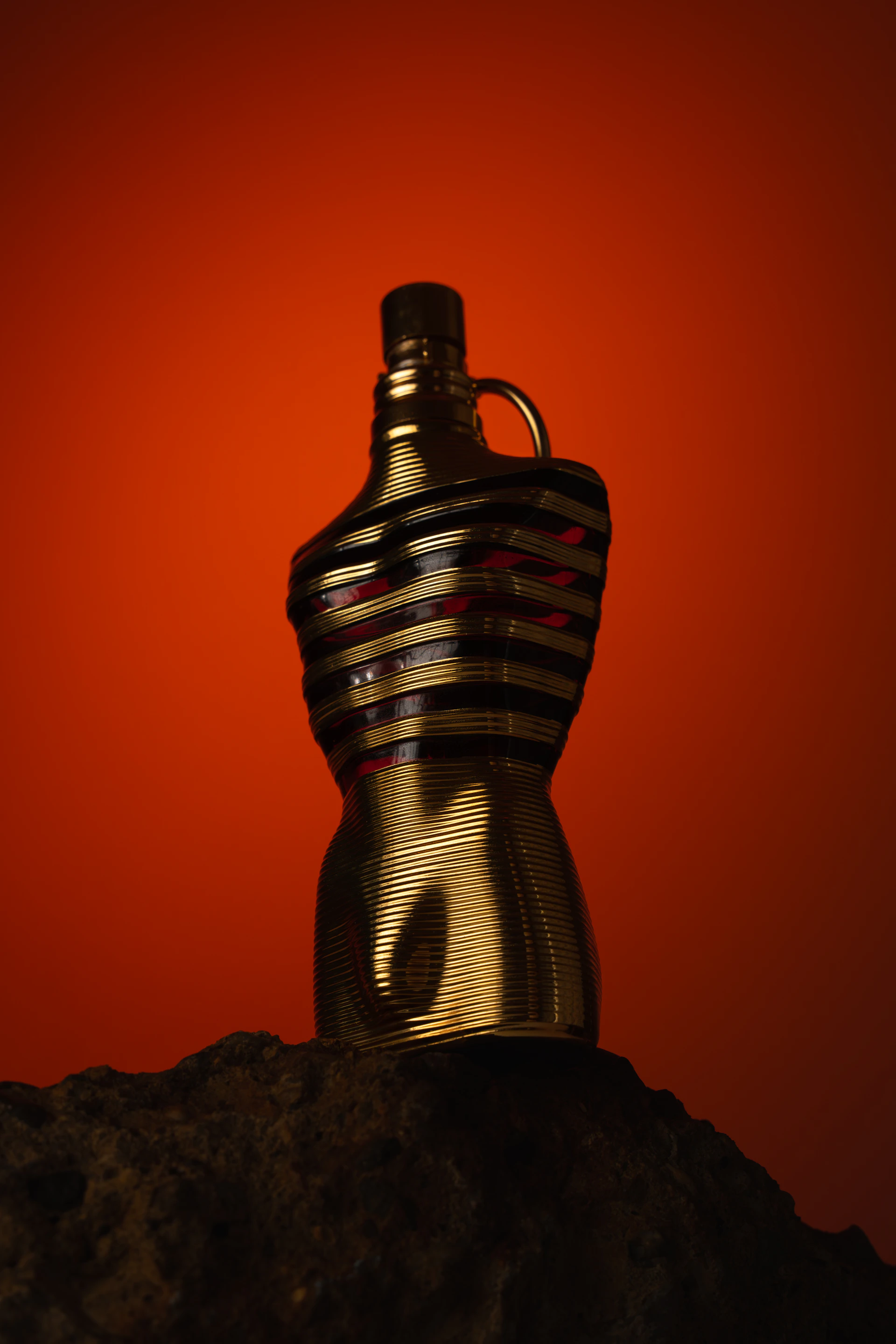 Gold bottle with striped design on rock