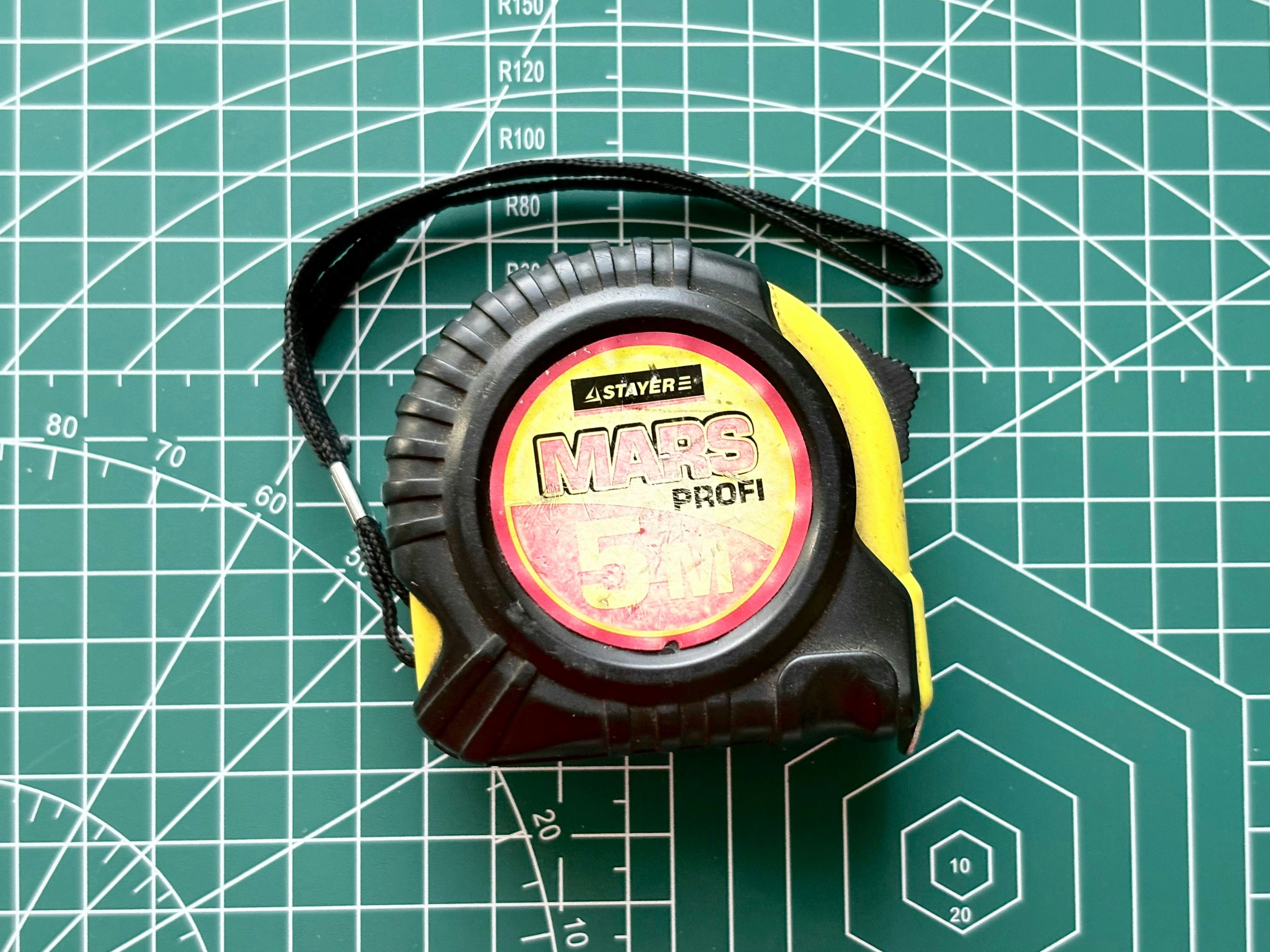 A yellow and black tape measure on a green grid