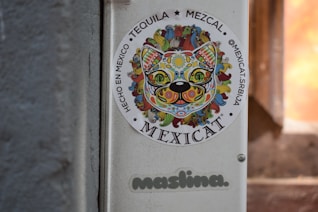 A colorful sticker of a cat with mexican-inspired designs.