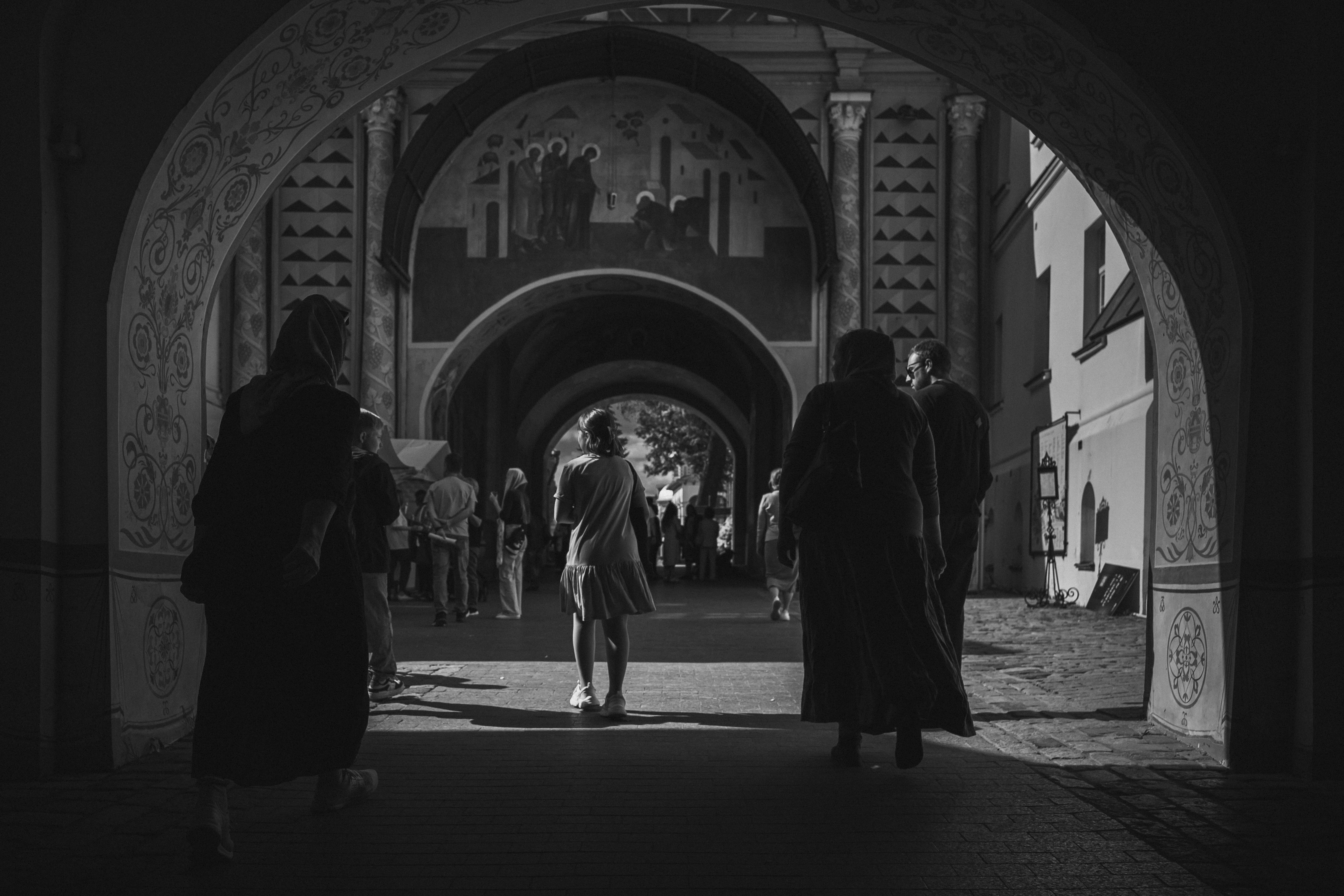 People walking through arched passageway with murals