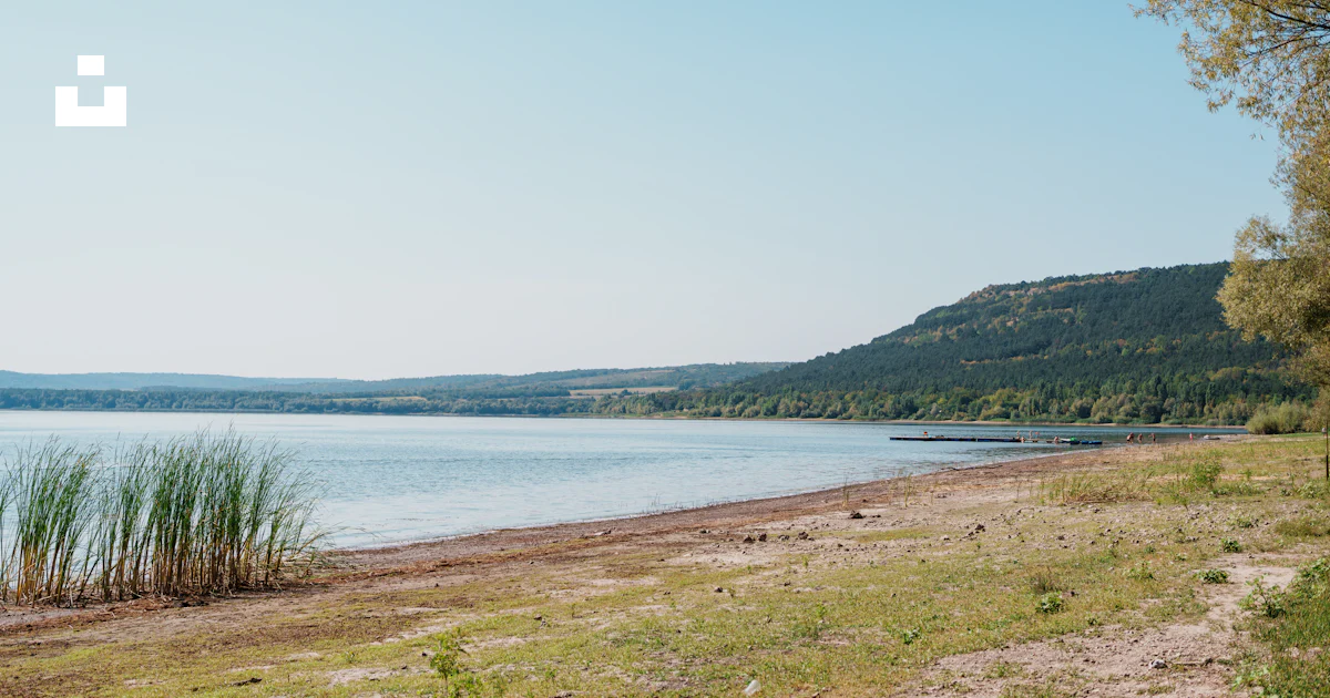 Lac calme avec un rivage herbeux et des collines lointaines. photo ...