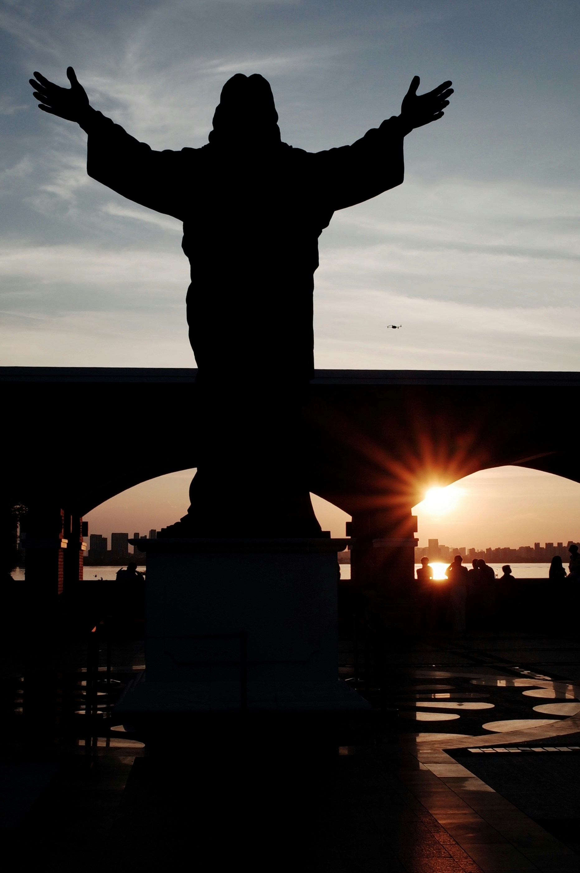Silhouette della statua di gesù con le braccia tese al tramonto.