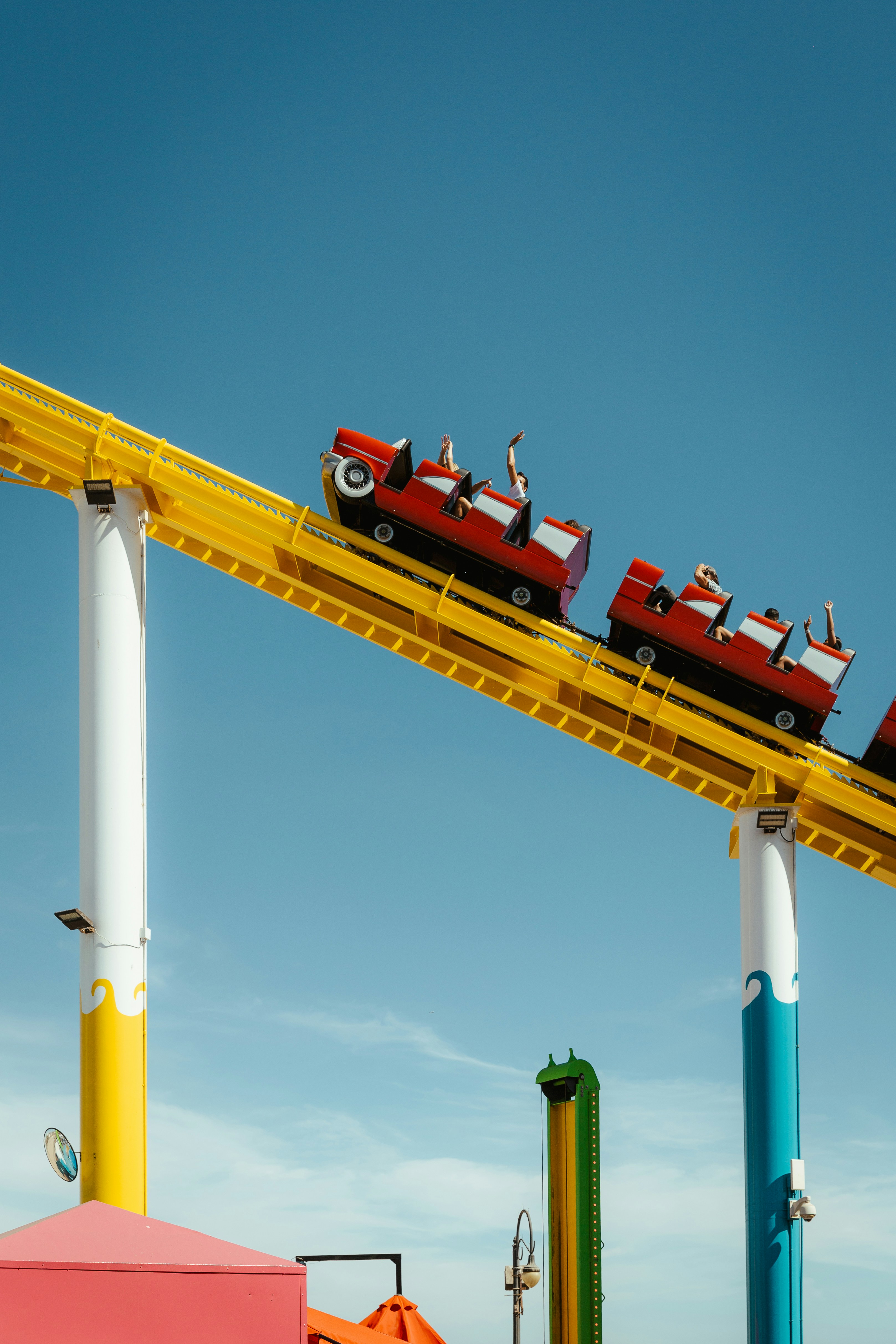 Red roller coaster cars ascend a yellow track.