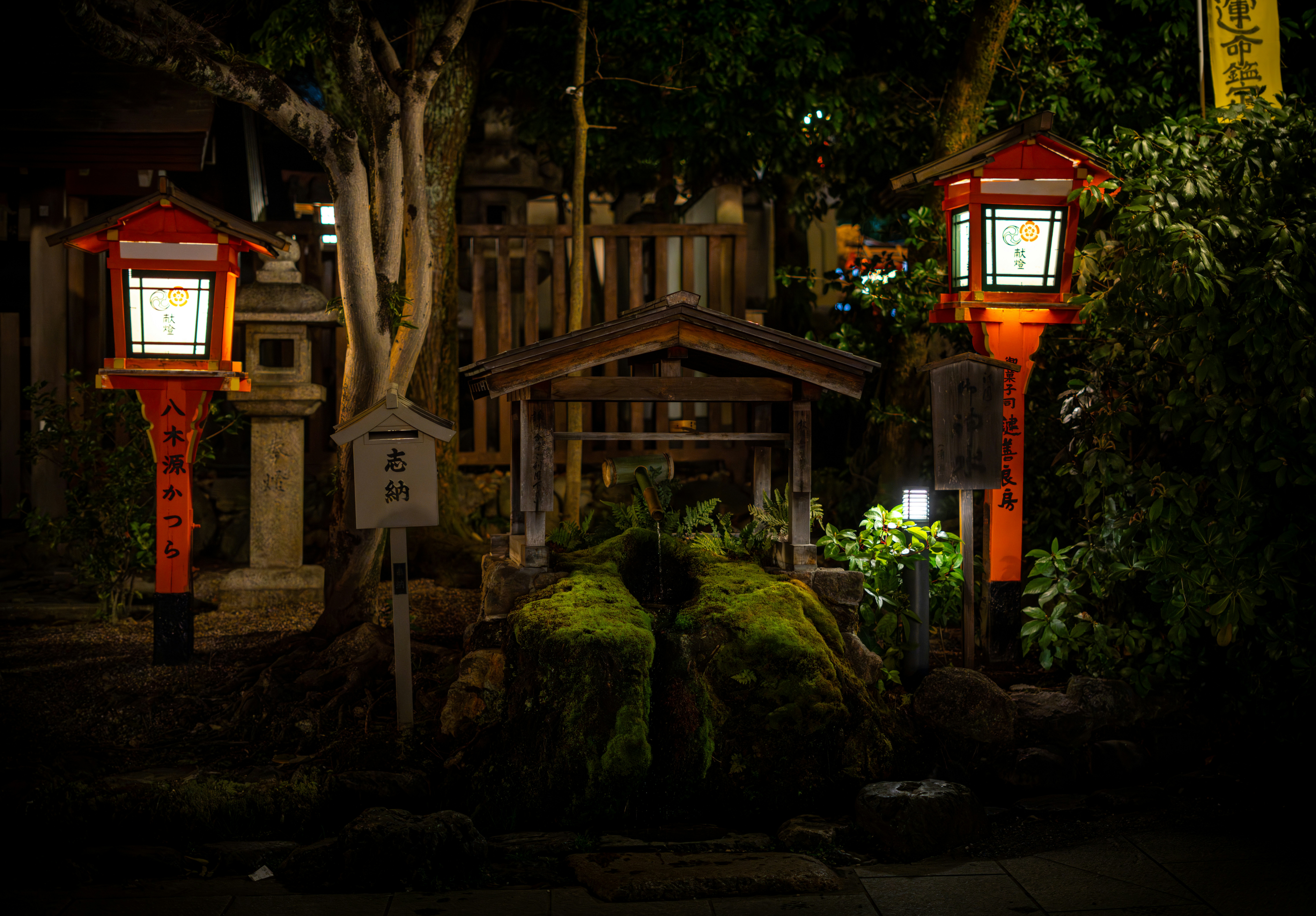 Two red lanterns illuminate a shrine at night.