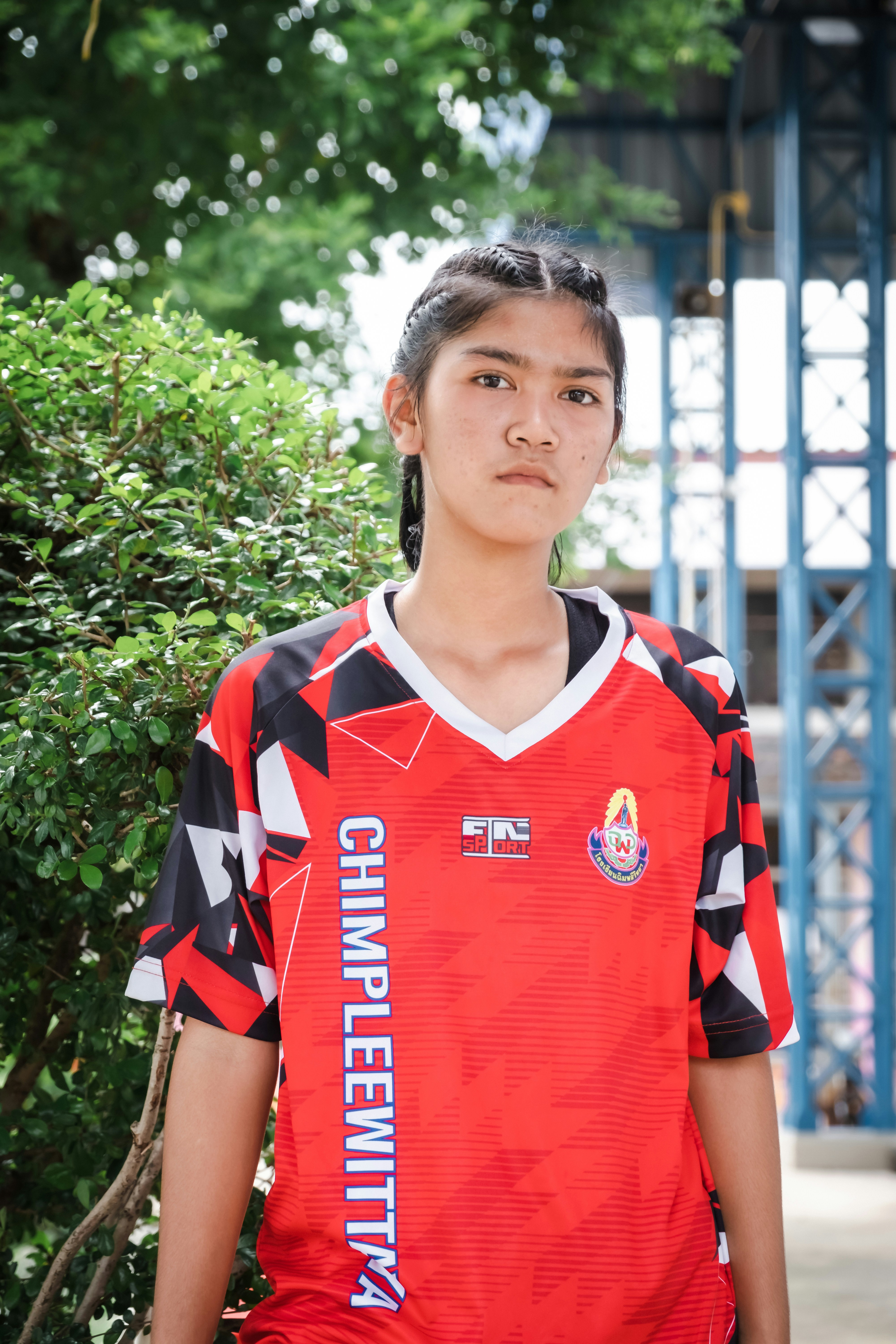 Giovane donna in una maglia sportiva rossa sta all'aperto.