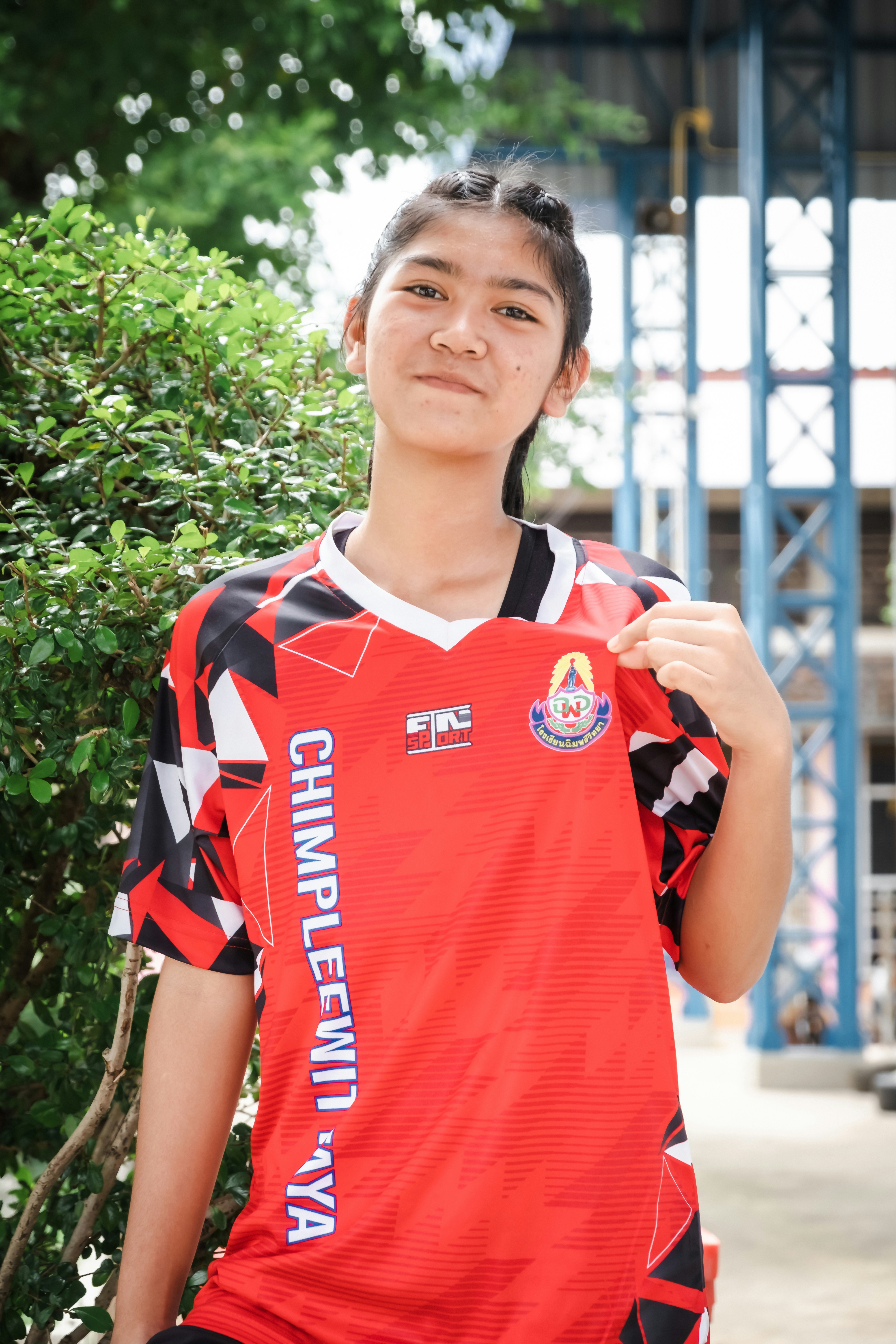 Una joven con una camiseta deportiva roja sonríe.