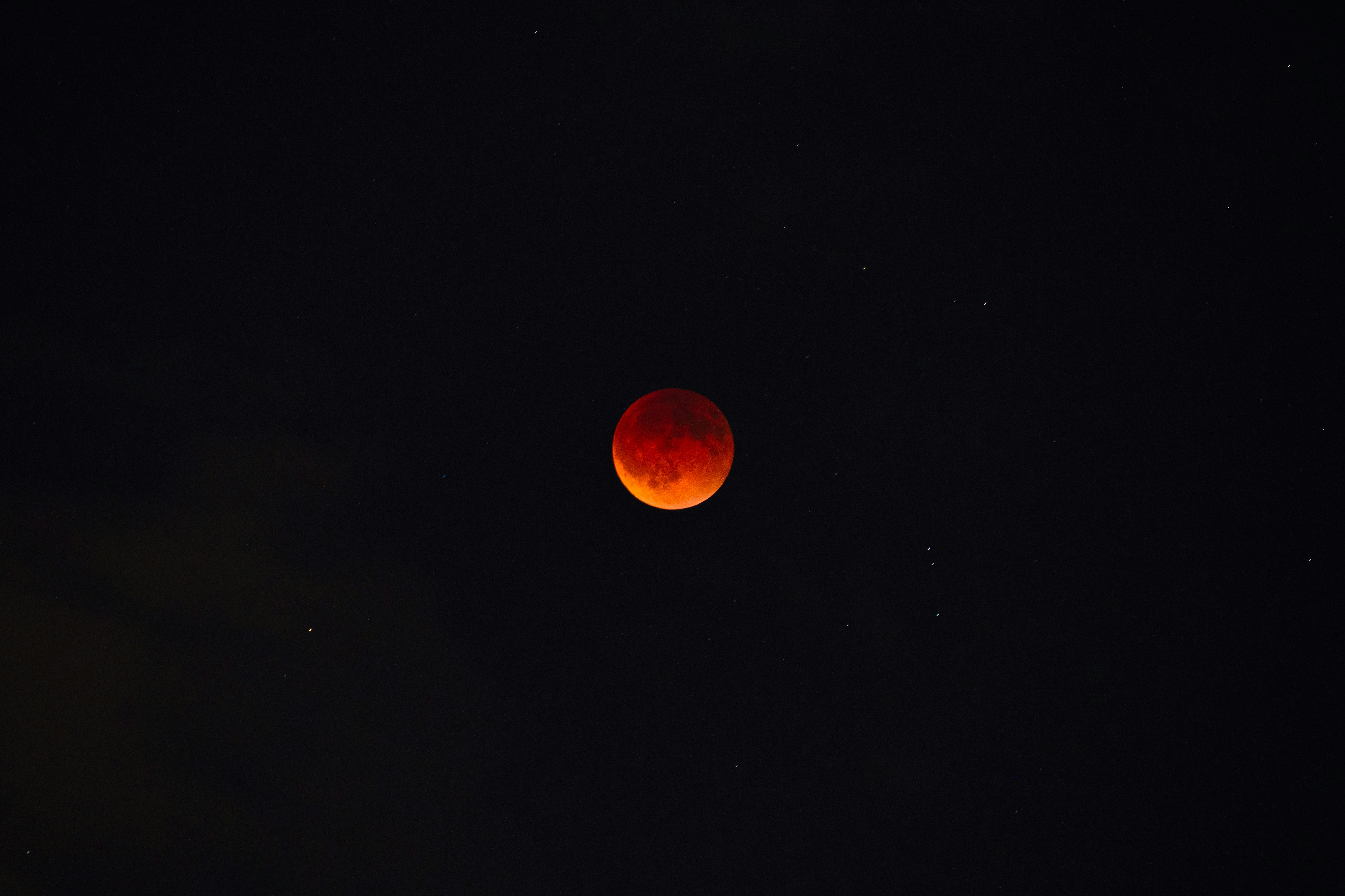 A blood moon glows in the starry night sky.