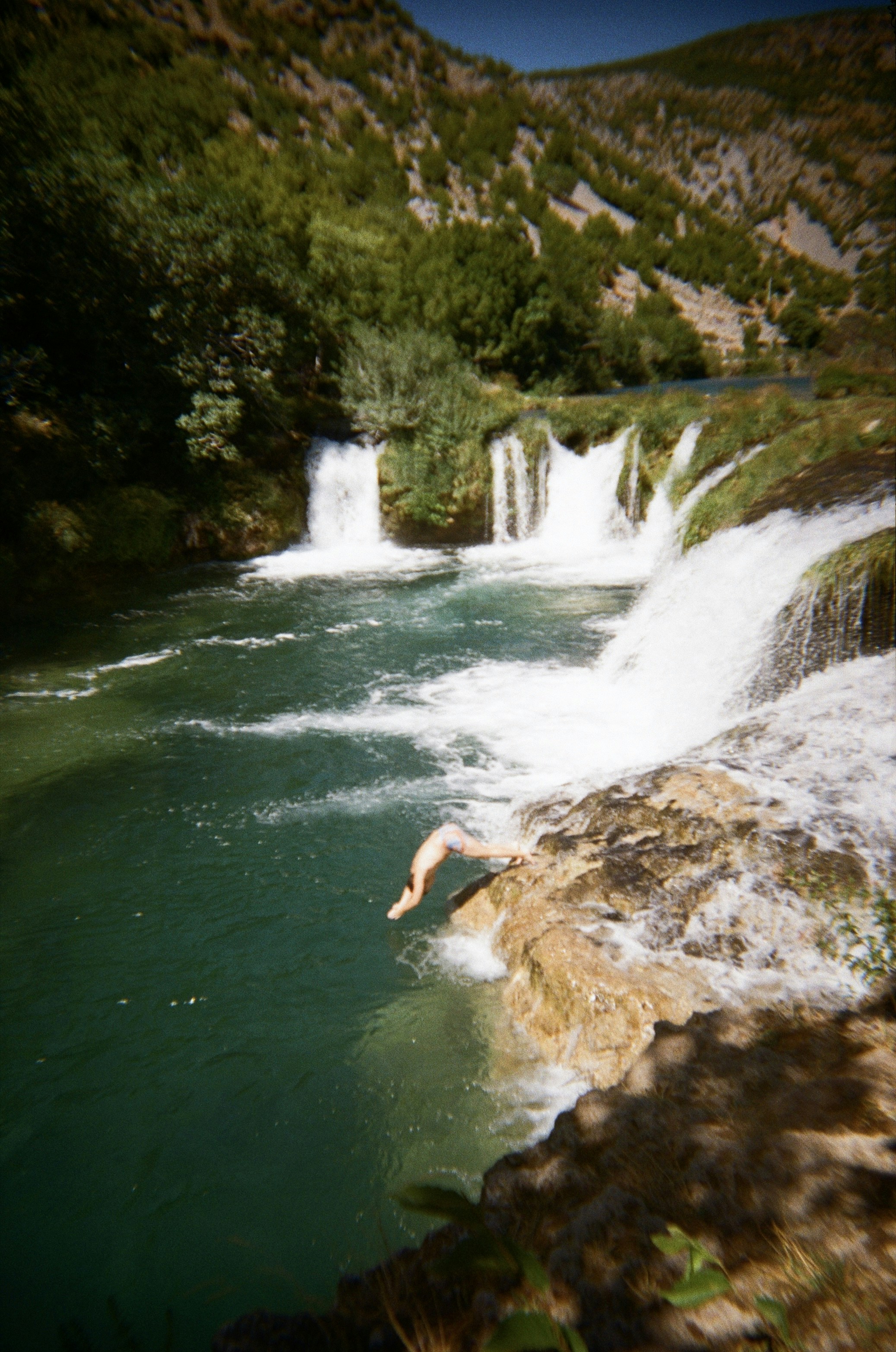 Person jumps into a waterfall pool