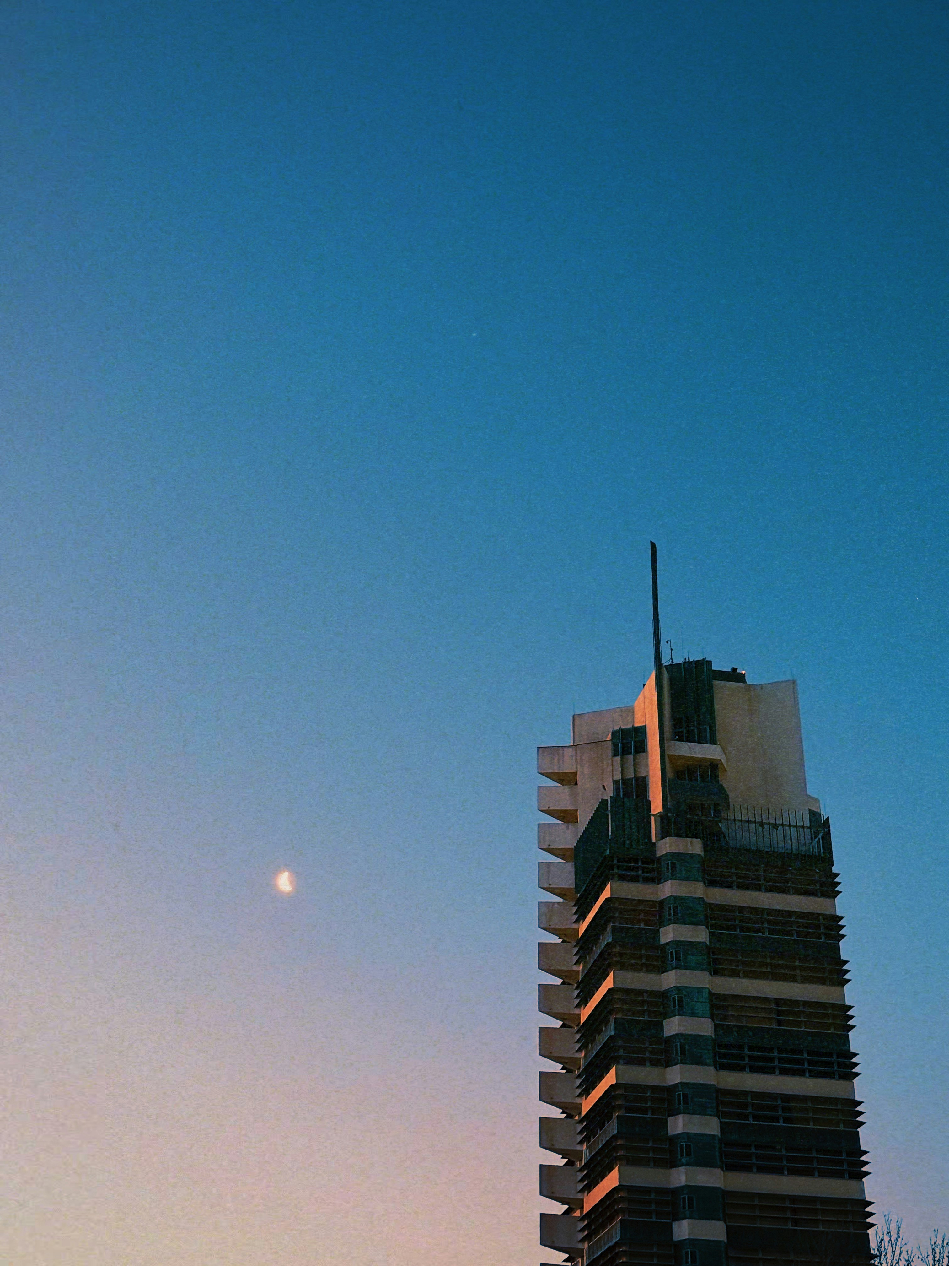 Modern skyscraper against a twilight sky with crescent moon