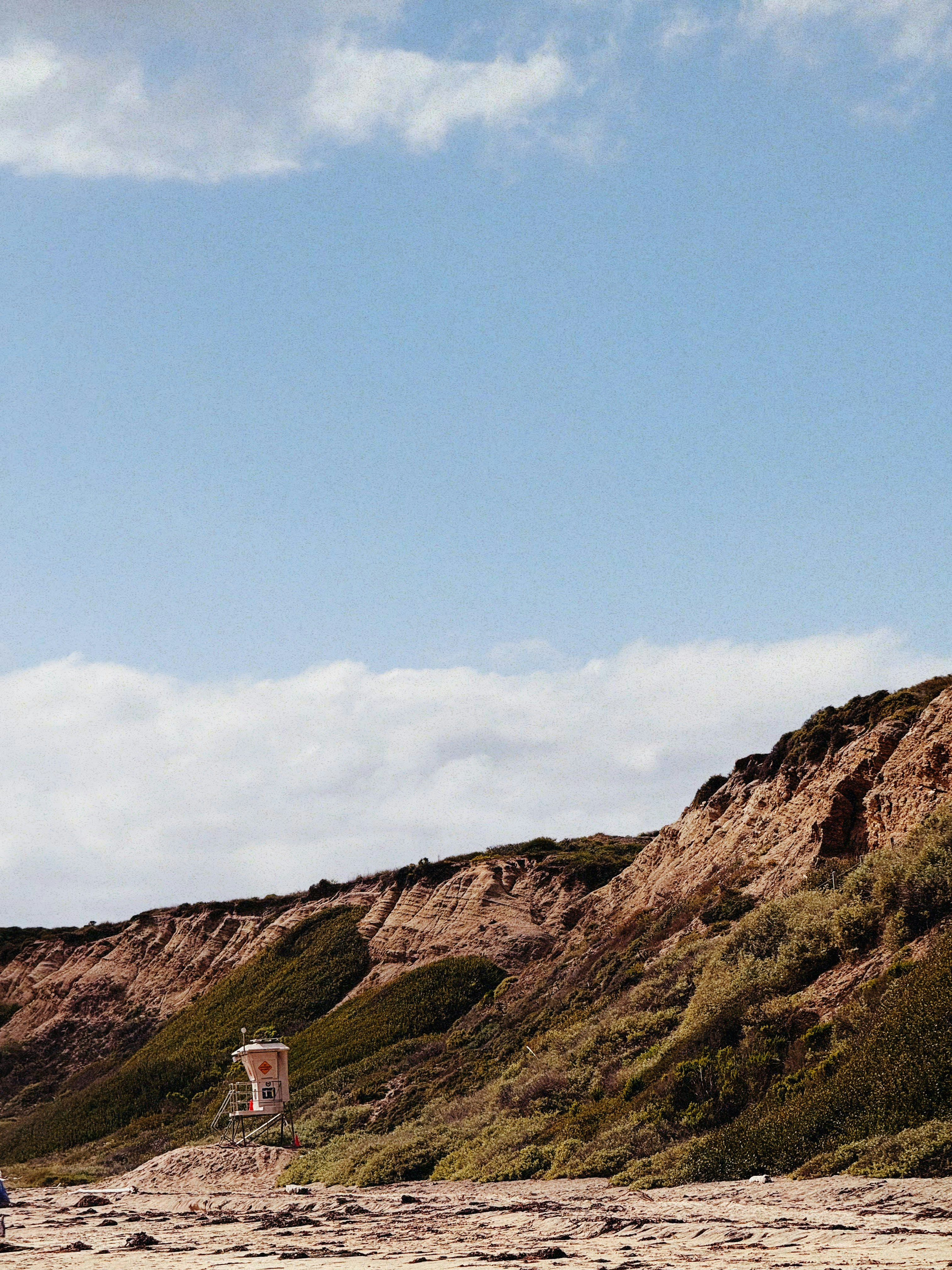 Lifeguard tower on a grassy cliff overlooking beach