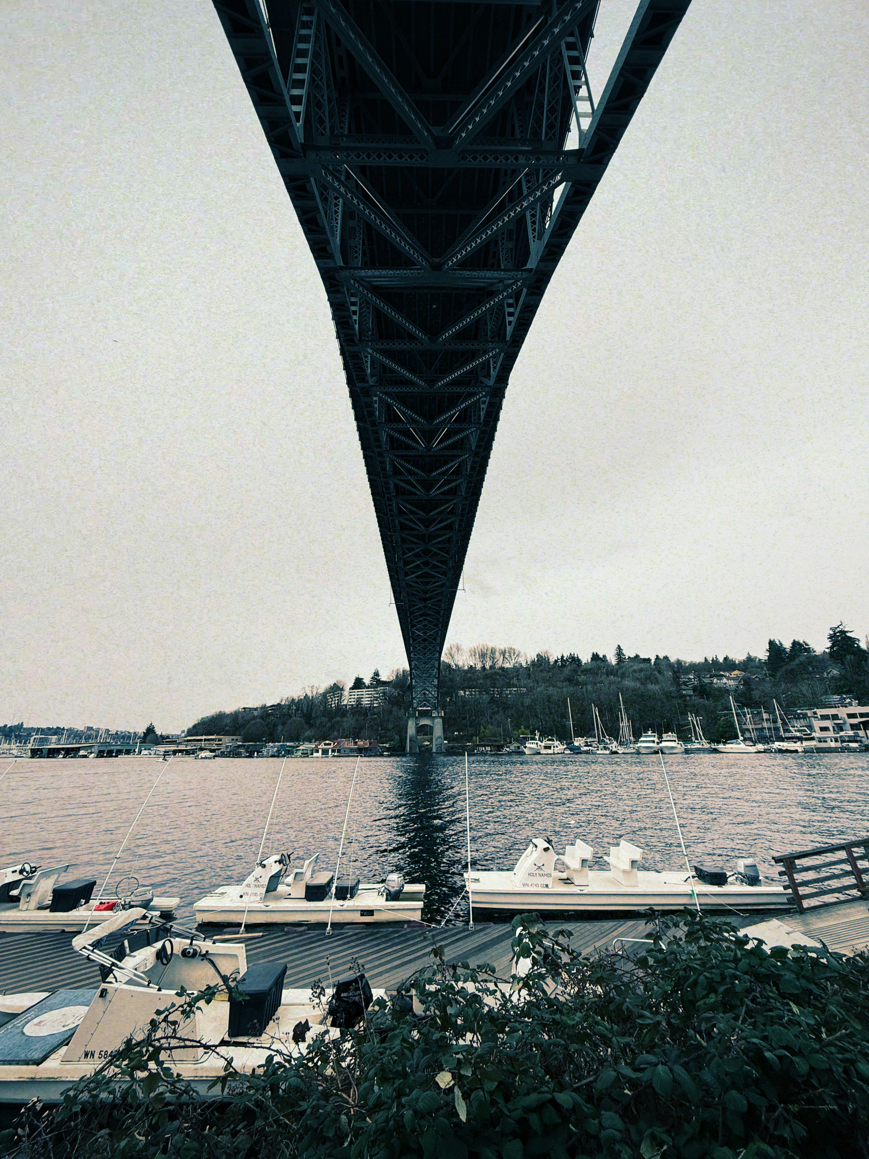 Looking up at a bridge over a calm bay with boats