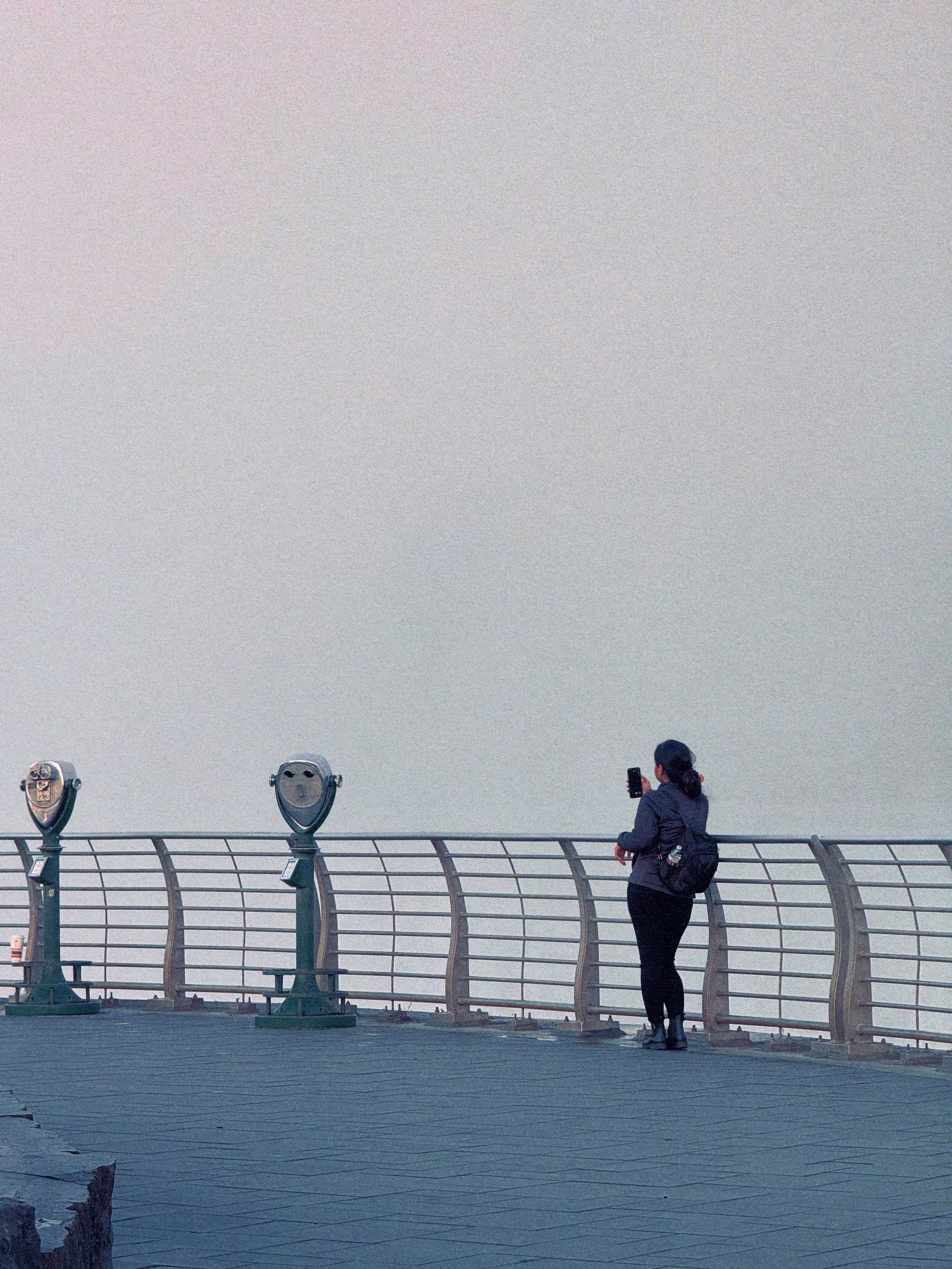 Woman taking photo with phone on scenic overlook