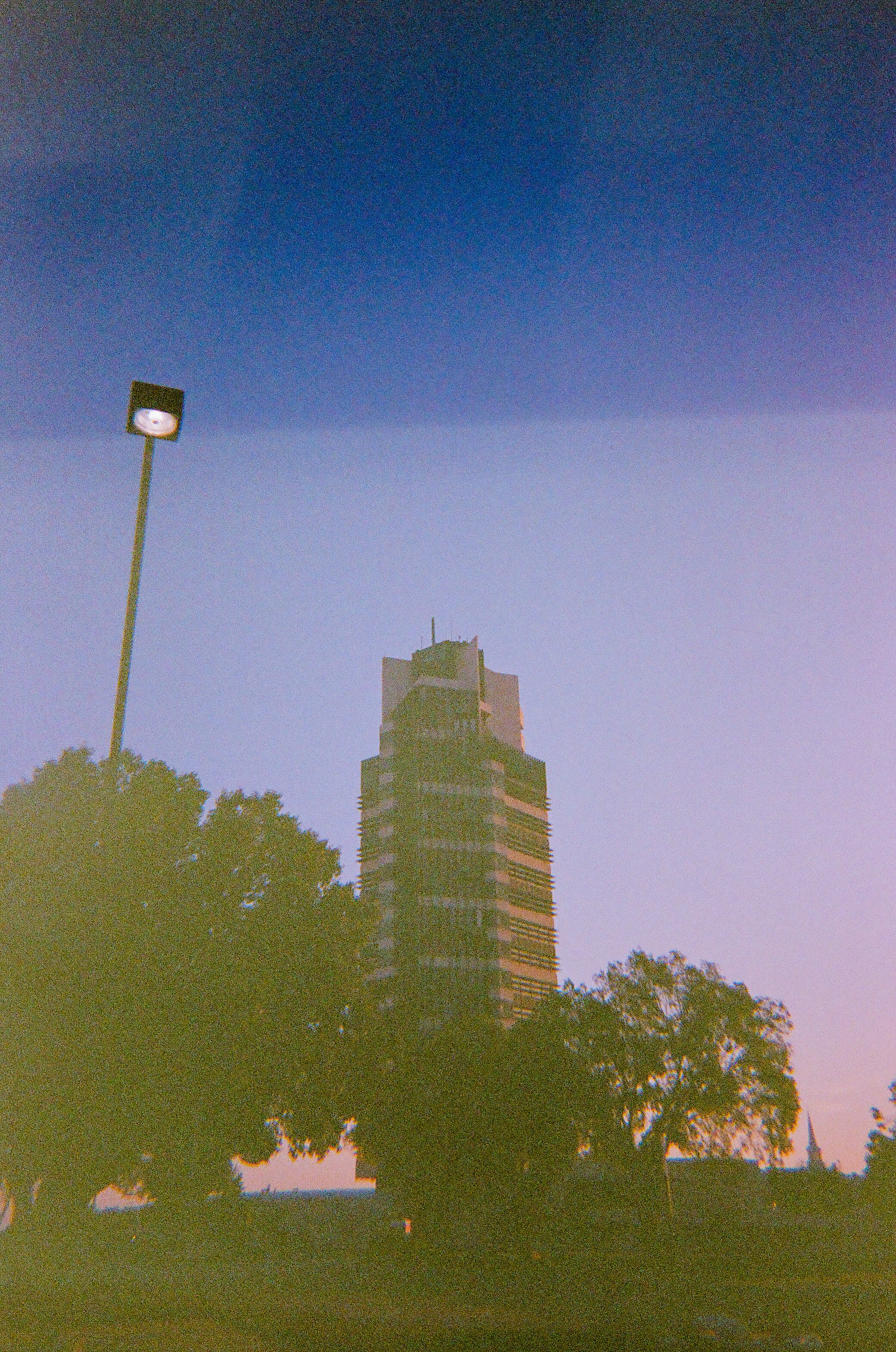 Tall building and street lamp against twilight sky.