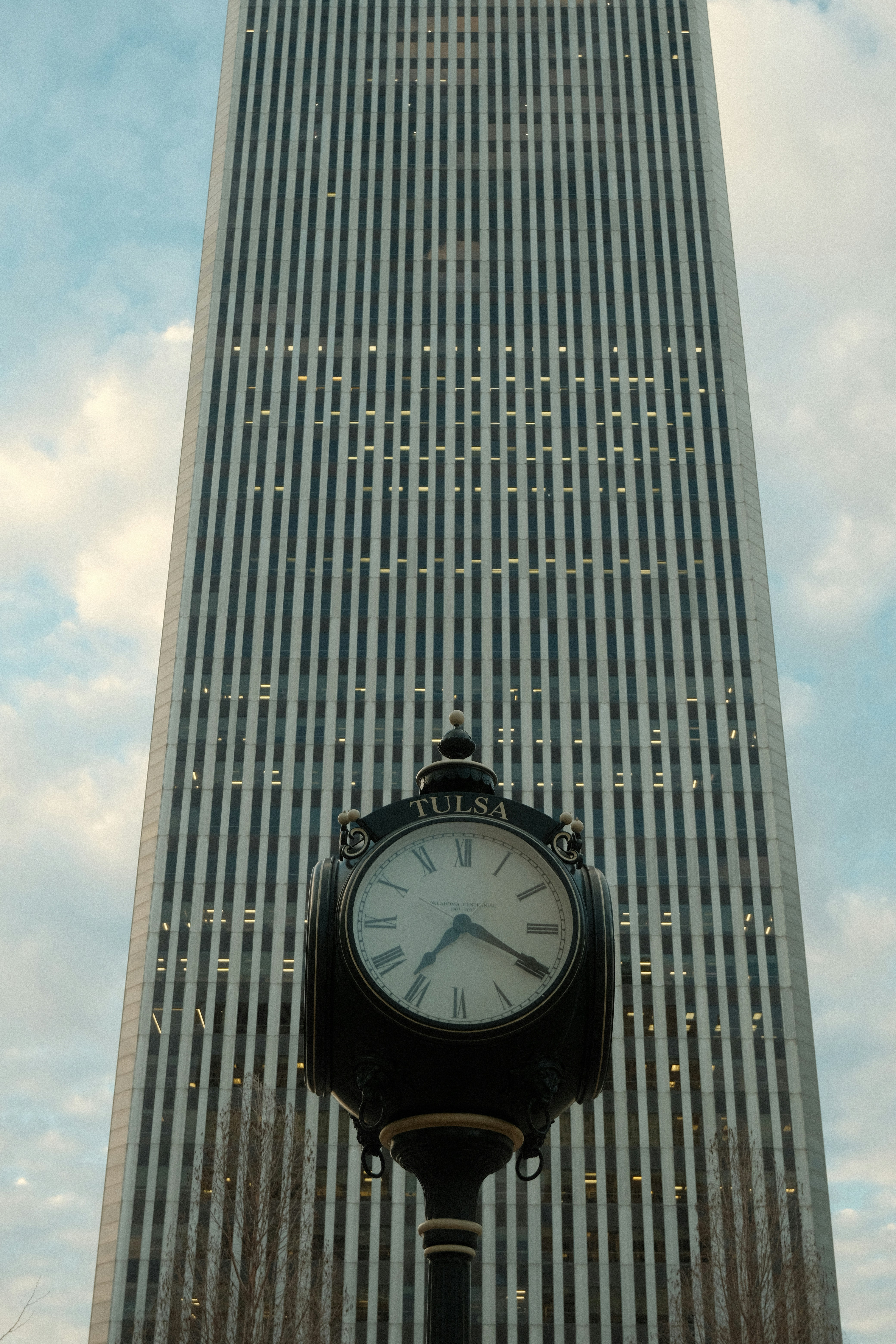 A vintage clock stands before a tall skyscraper.