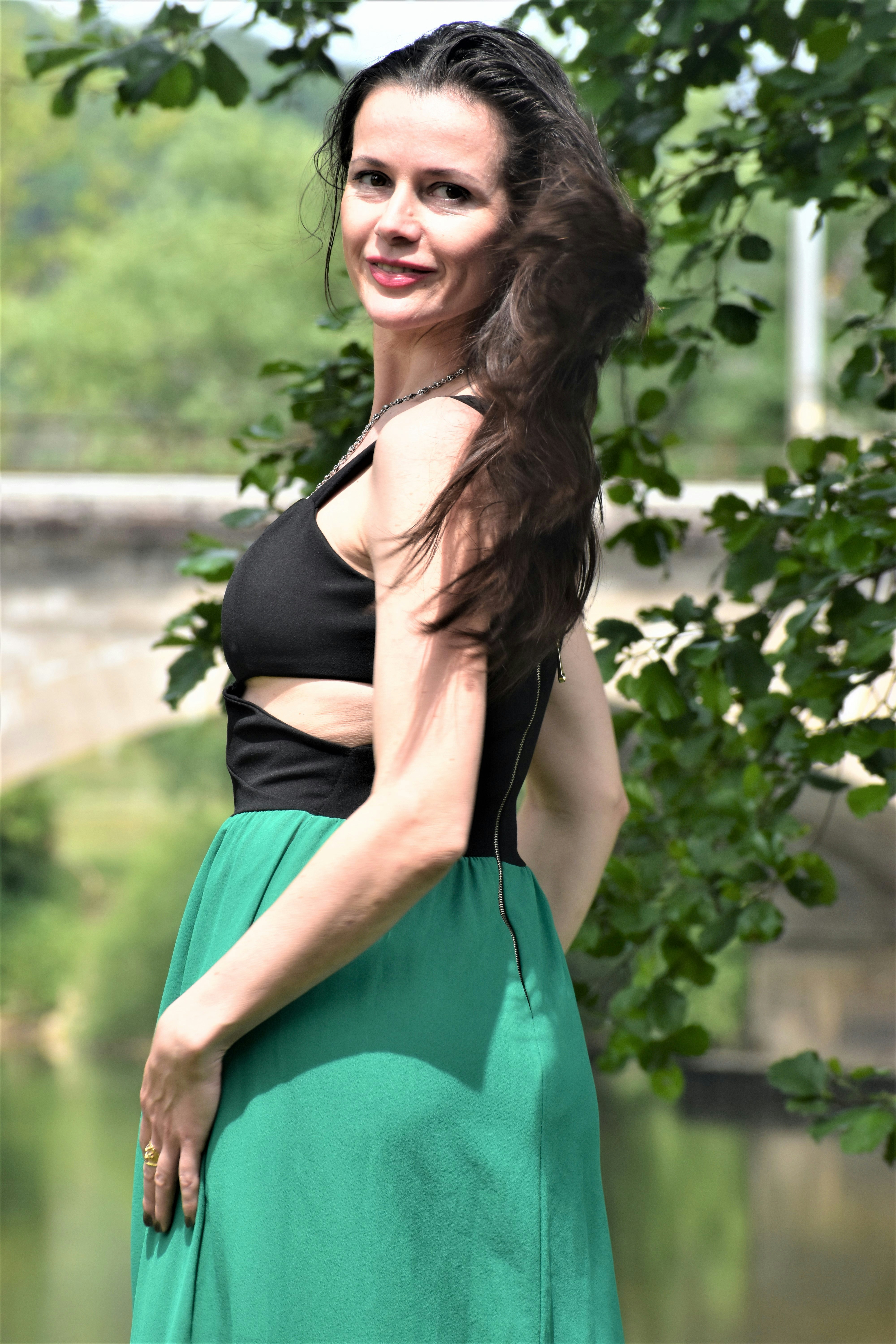 Woman in black and green dress by a river