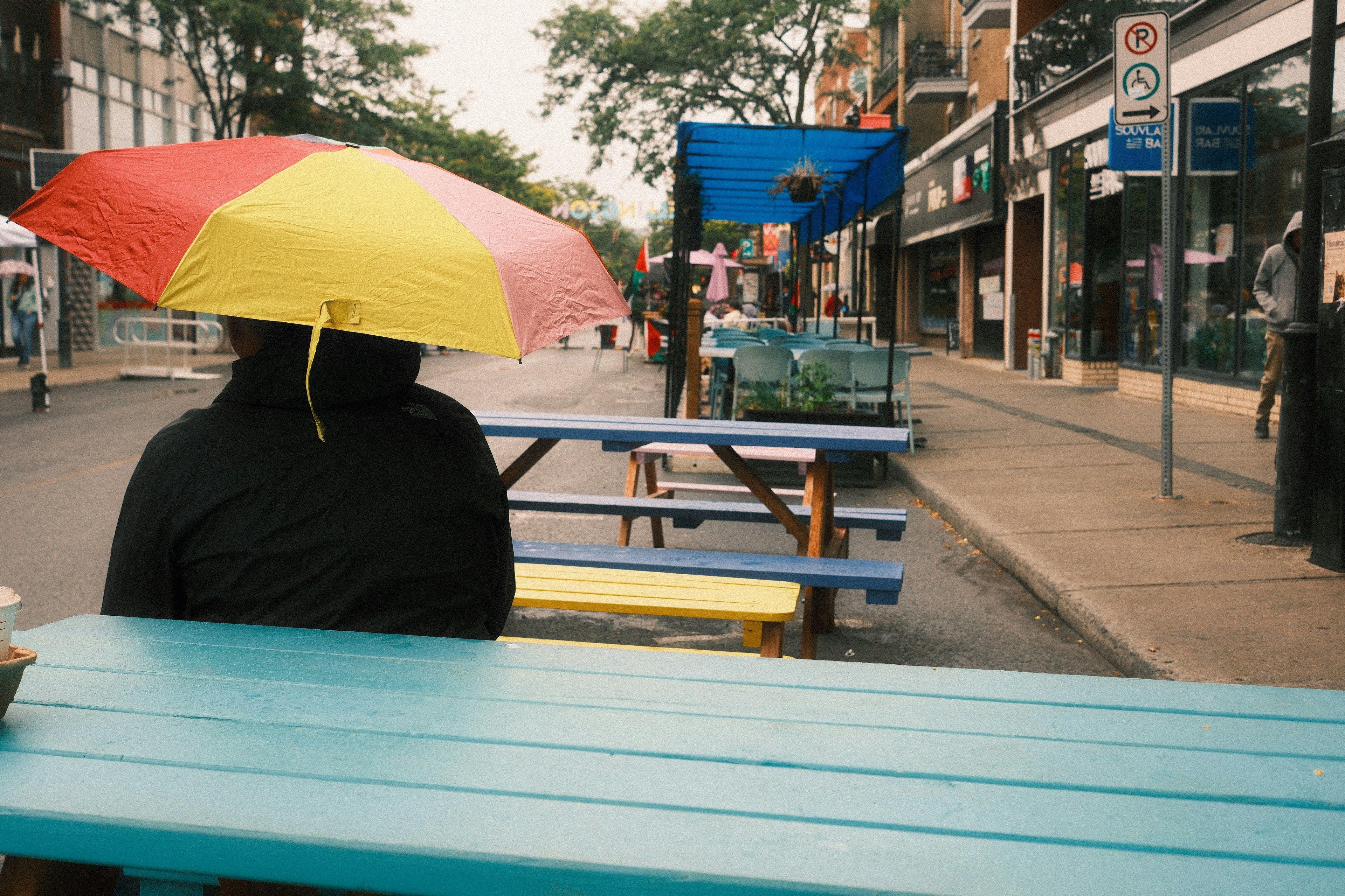 Person under colorful umbrella at outdoor cafe