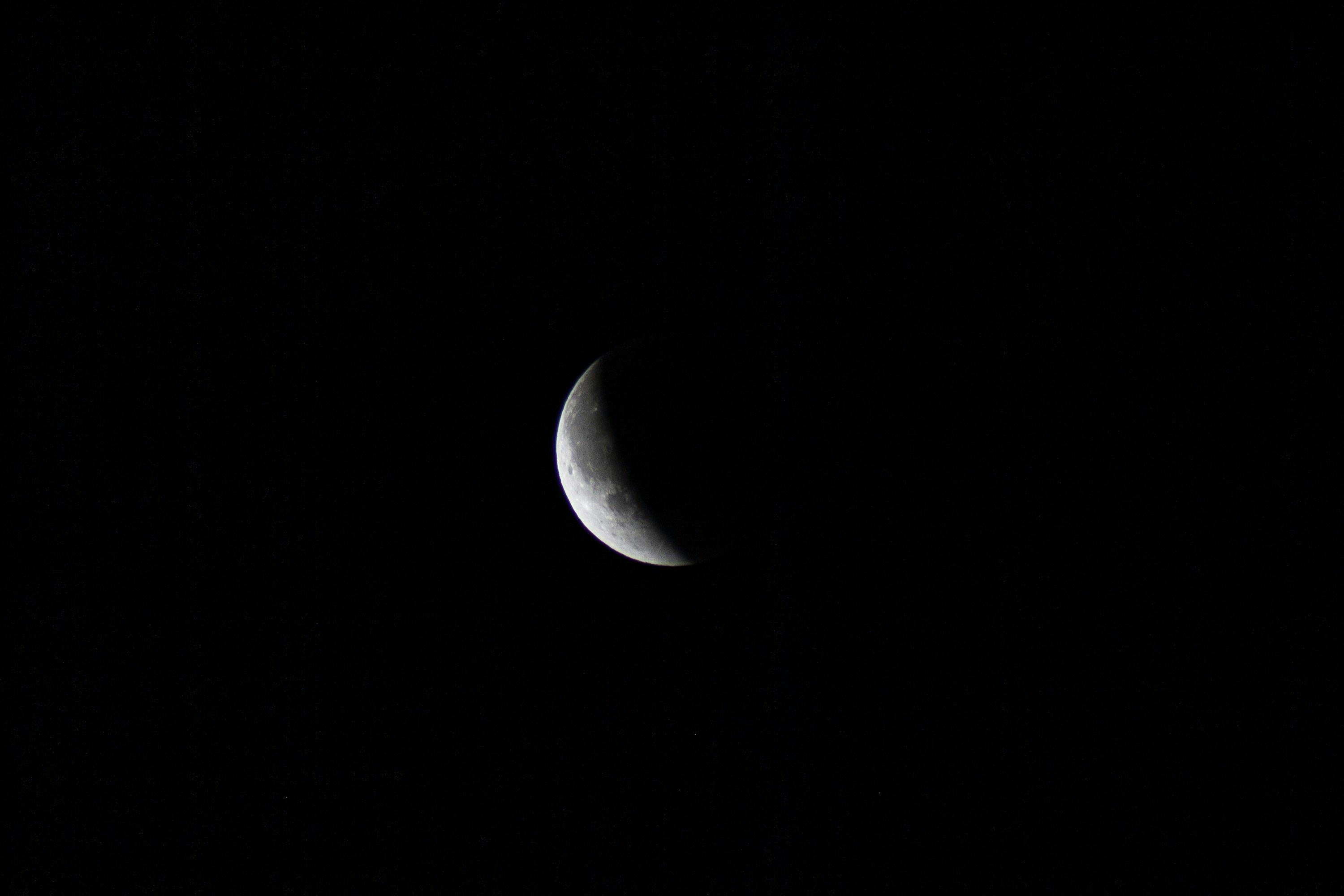 A crescent moon shines in the dark night sky.