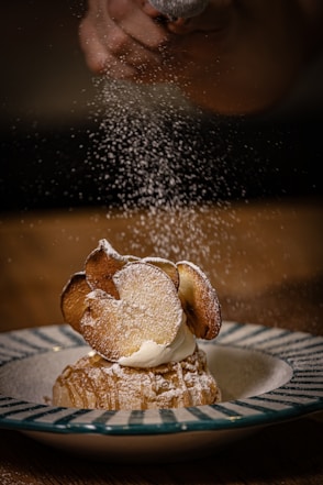 Powdered sugar is sprinkled over a dessert.