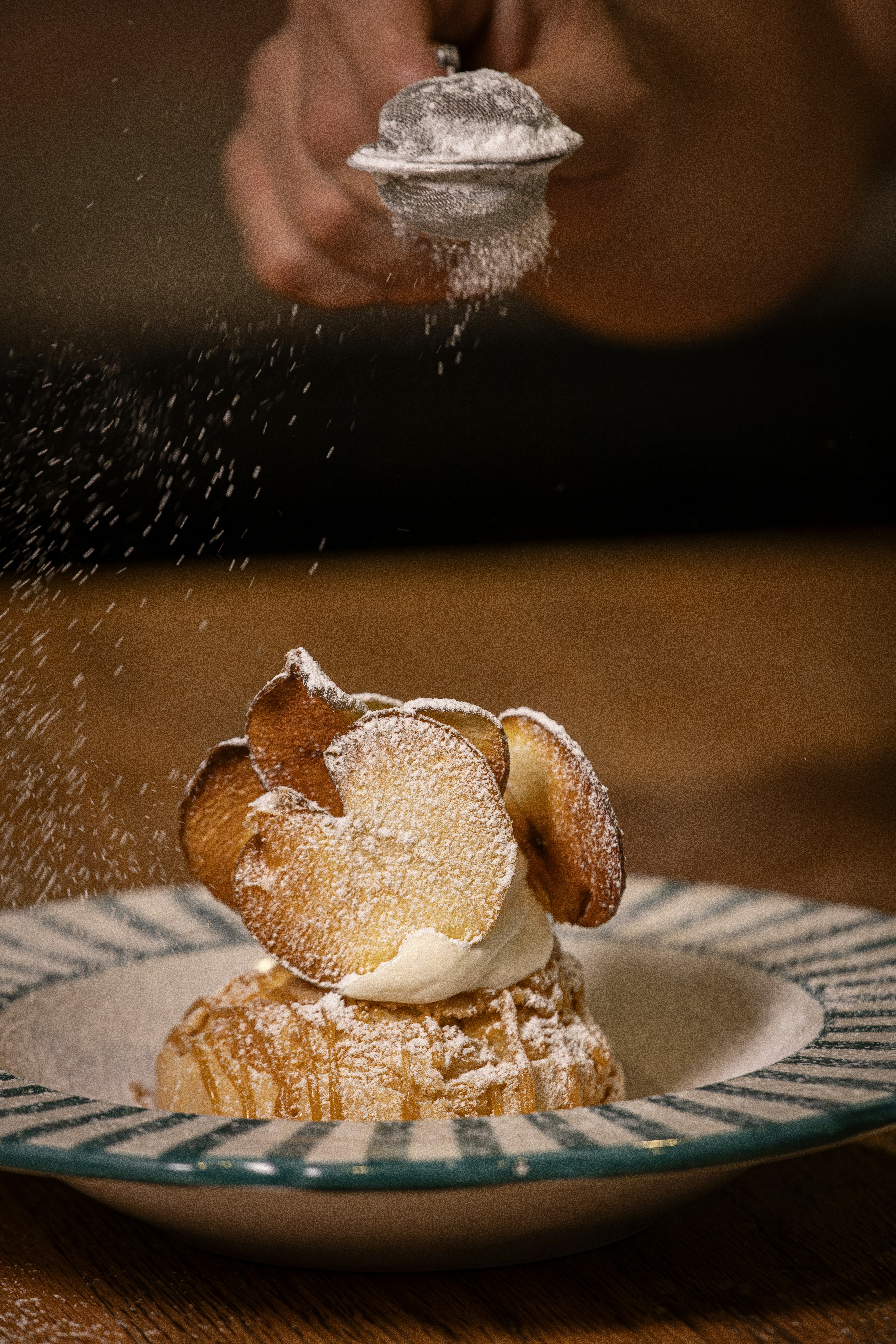 Chef dusting powdered sugar onto a dessert