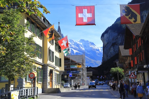 Swiss flags hang over a street with mountains behind.