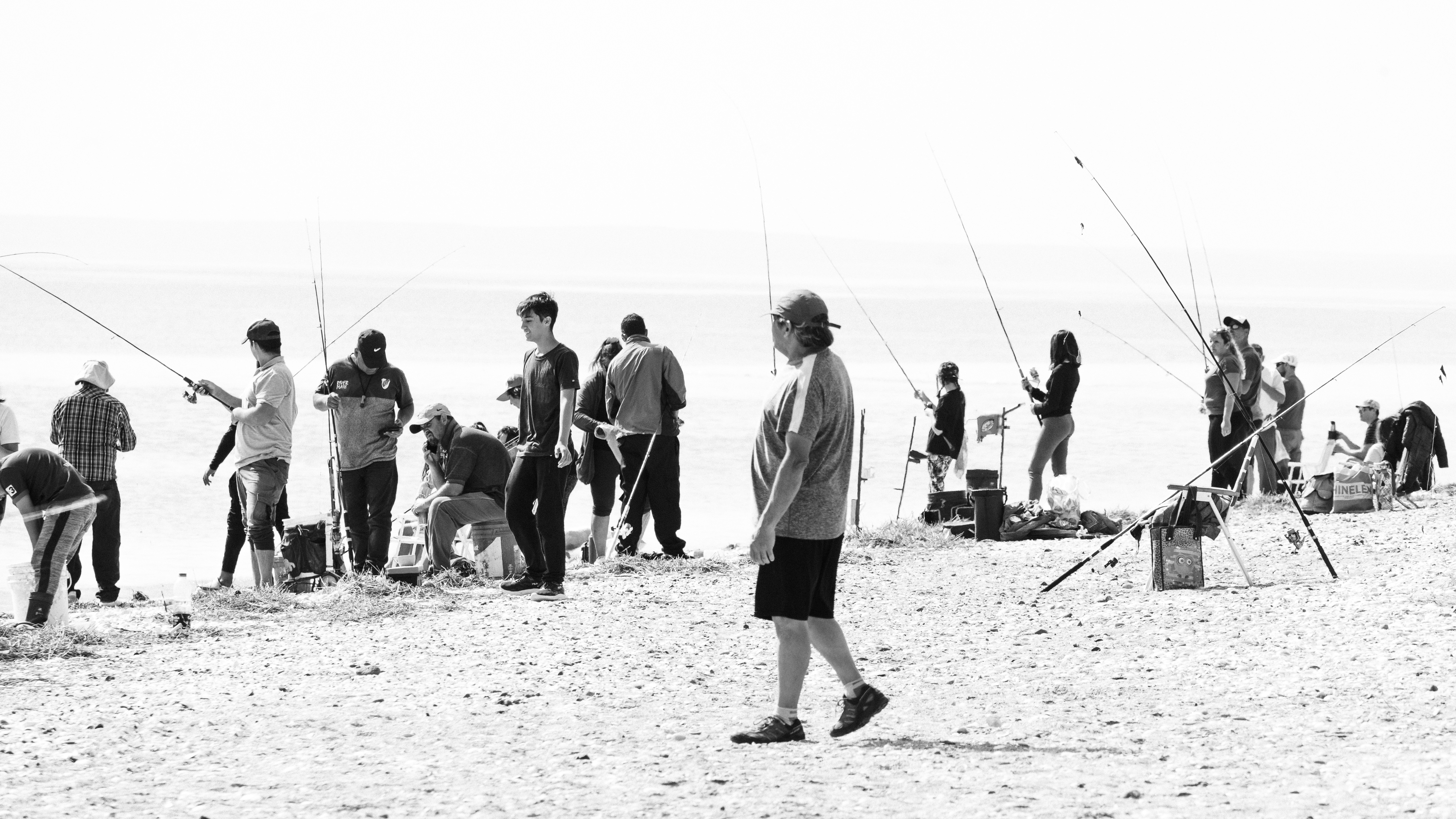 People fishing on a sandy beach with rods.