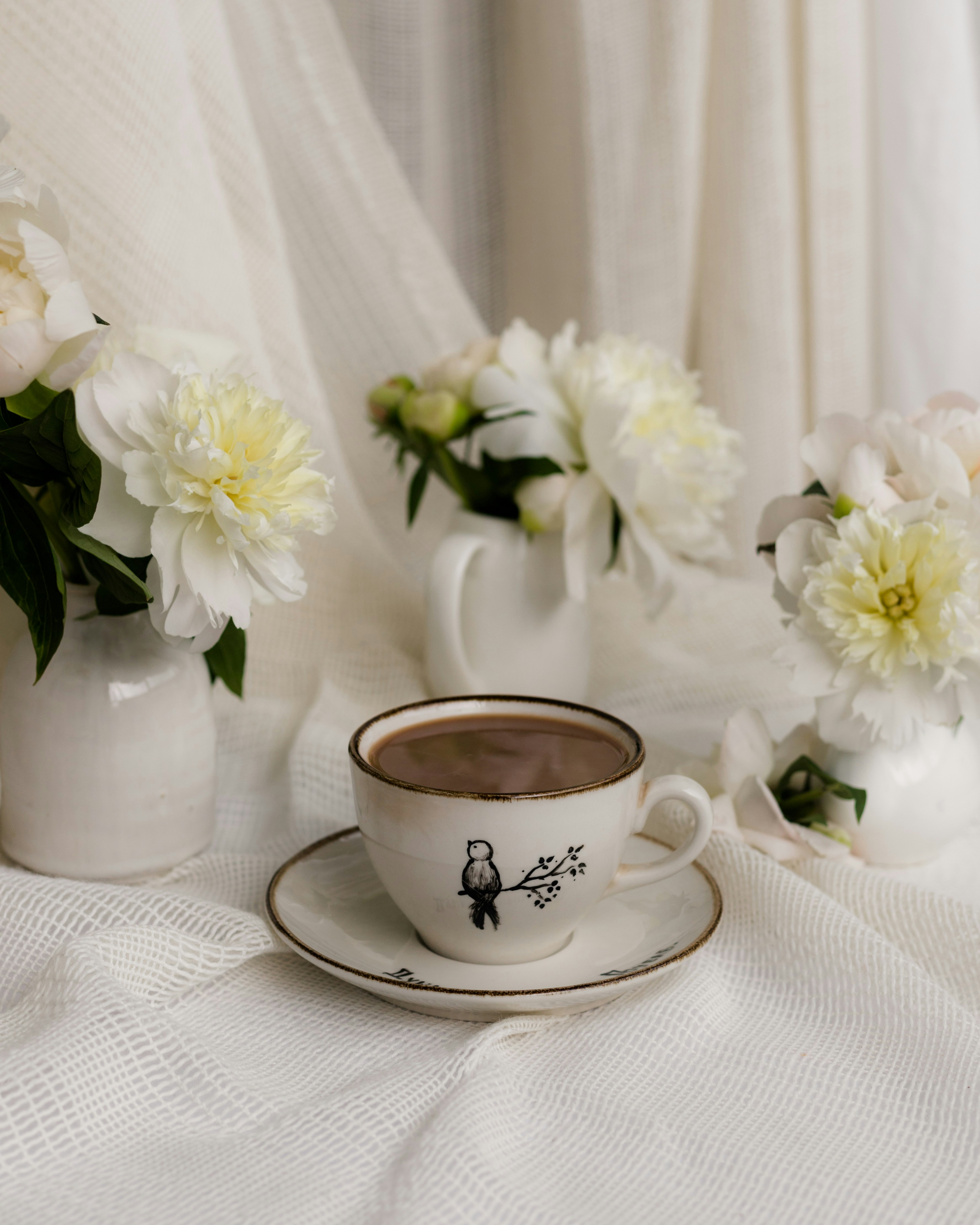 Una tazzina di caffè circondata da fiori bianchi