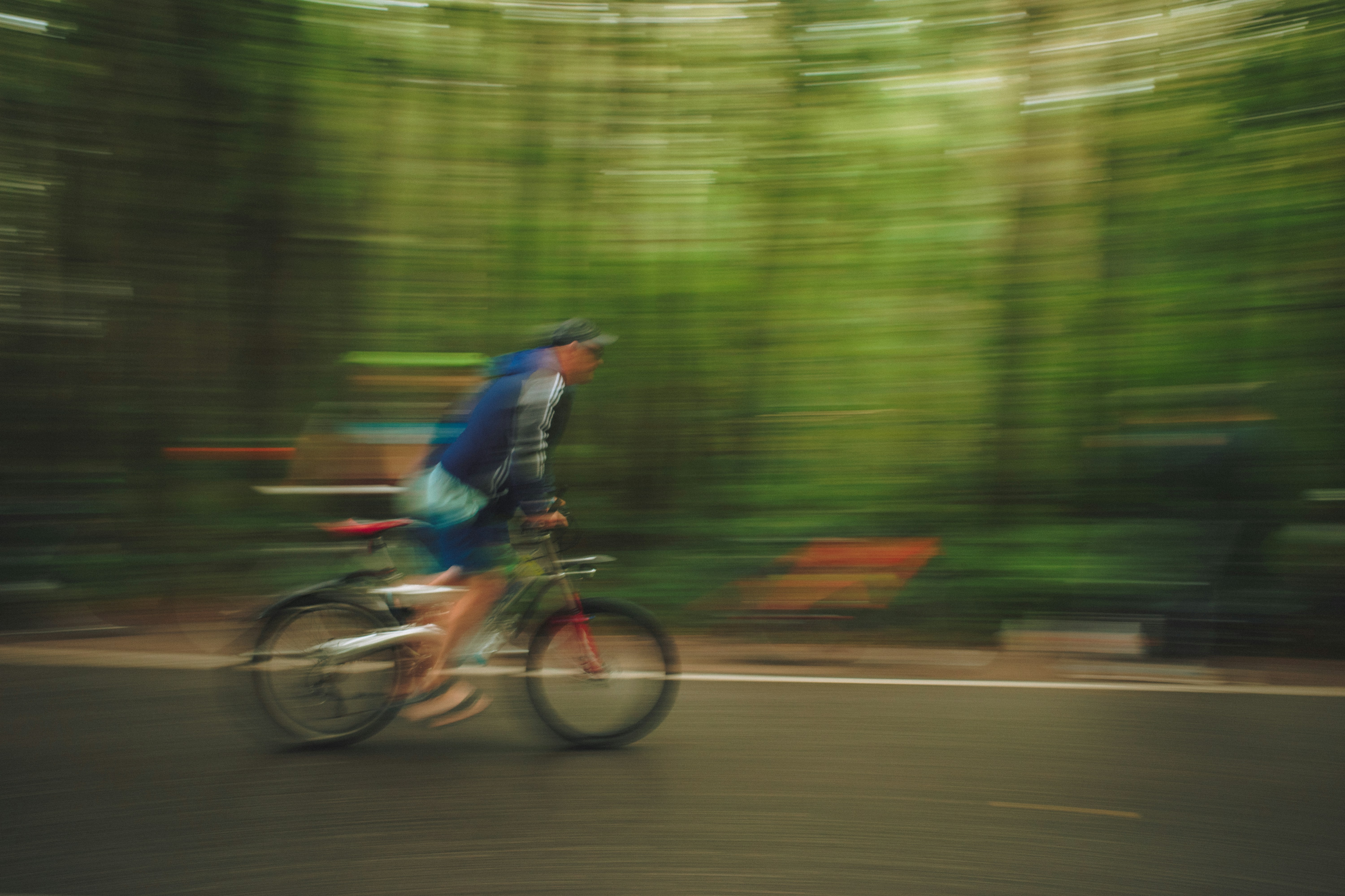Person cycling on a road with blurred trees