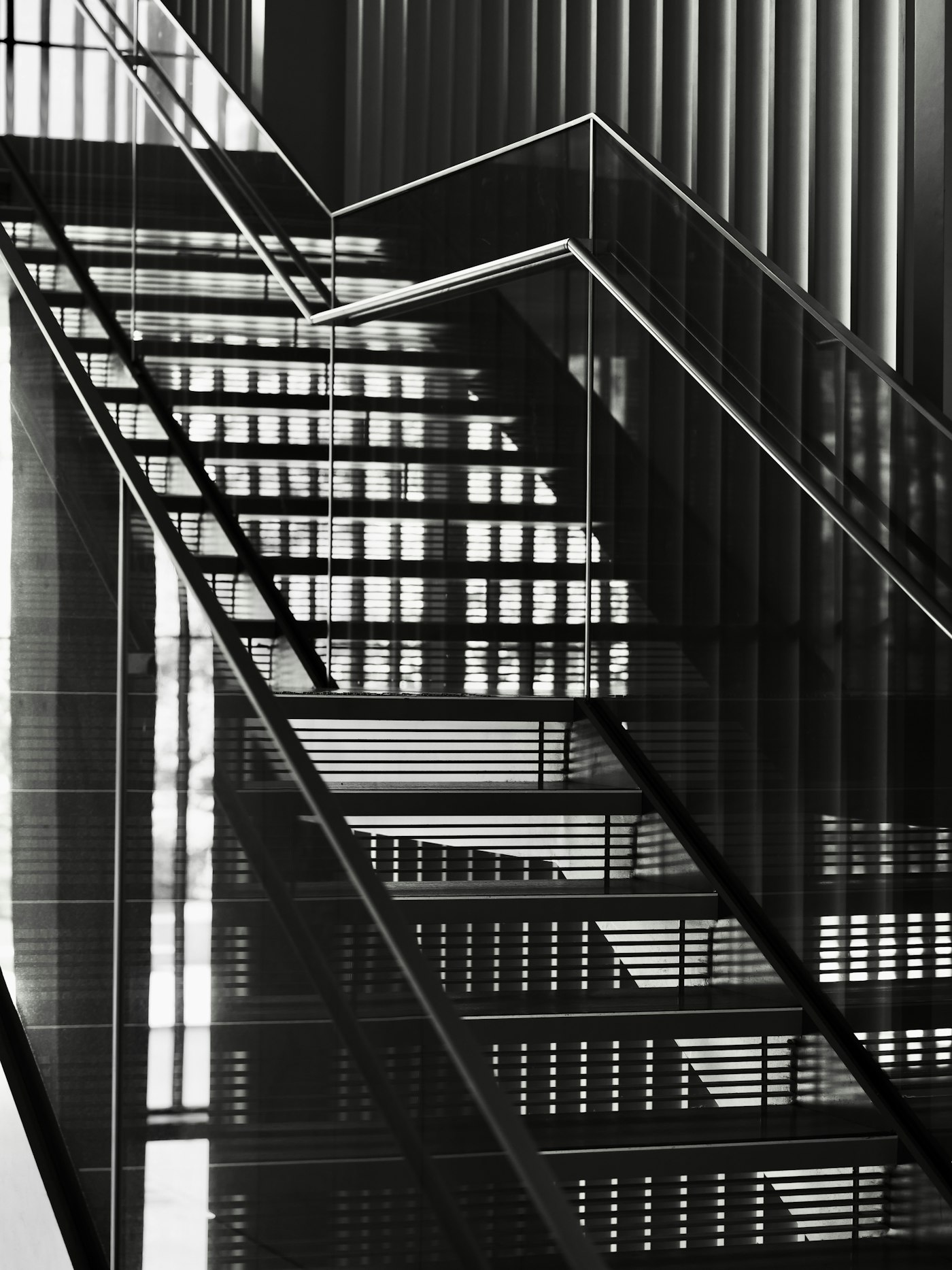Modern glass and metal staircase railing with light patterns