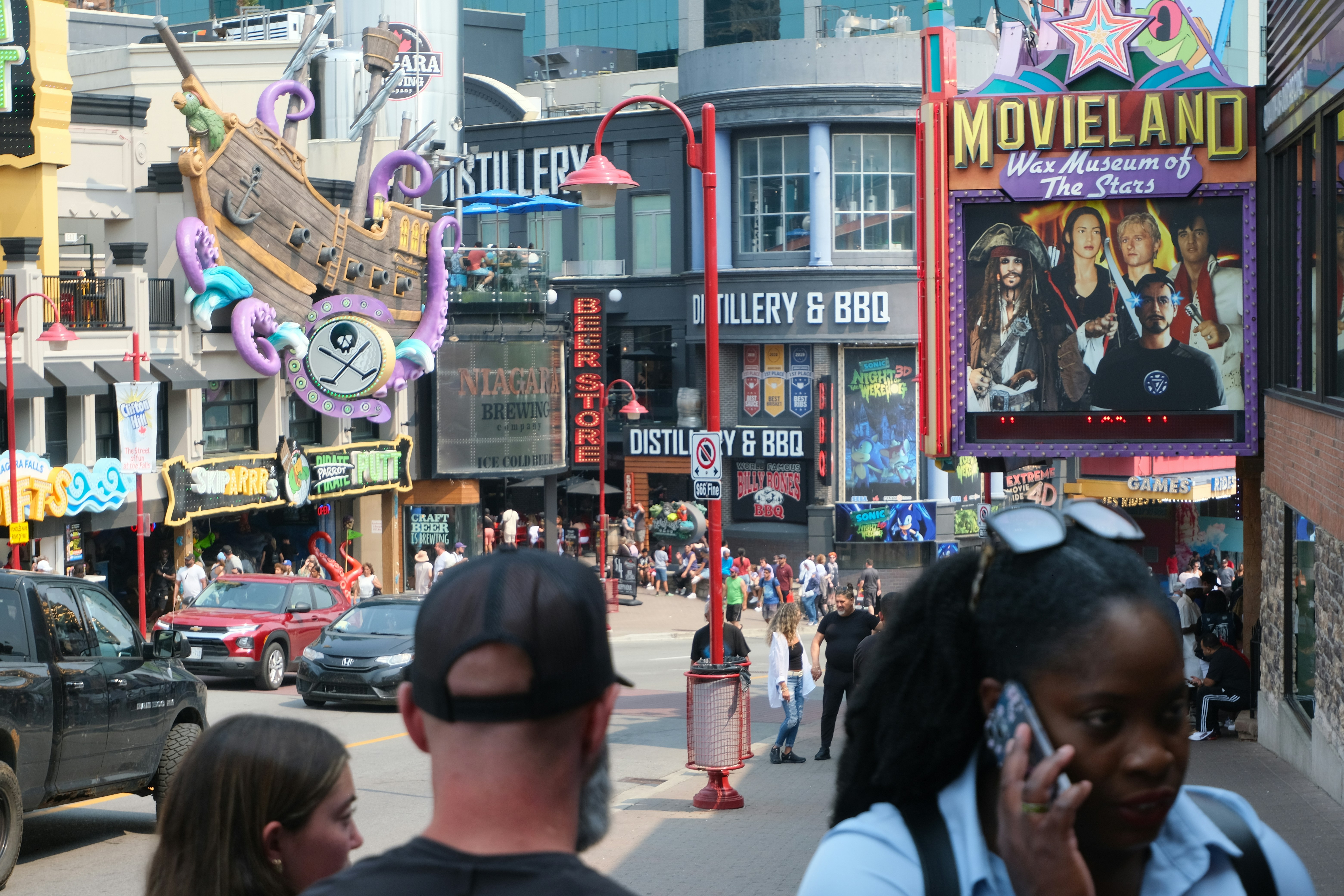 Rua movimentada com lojas e pessoas em um dia ensolarado.