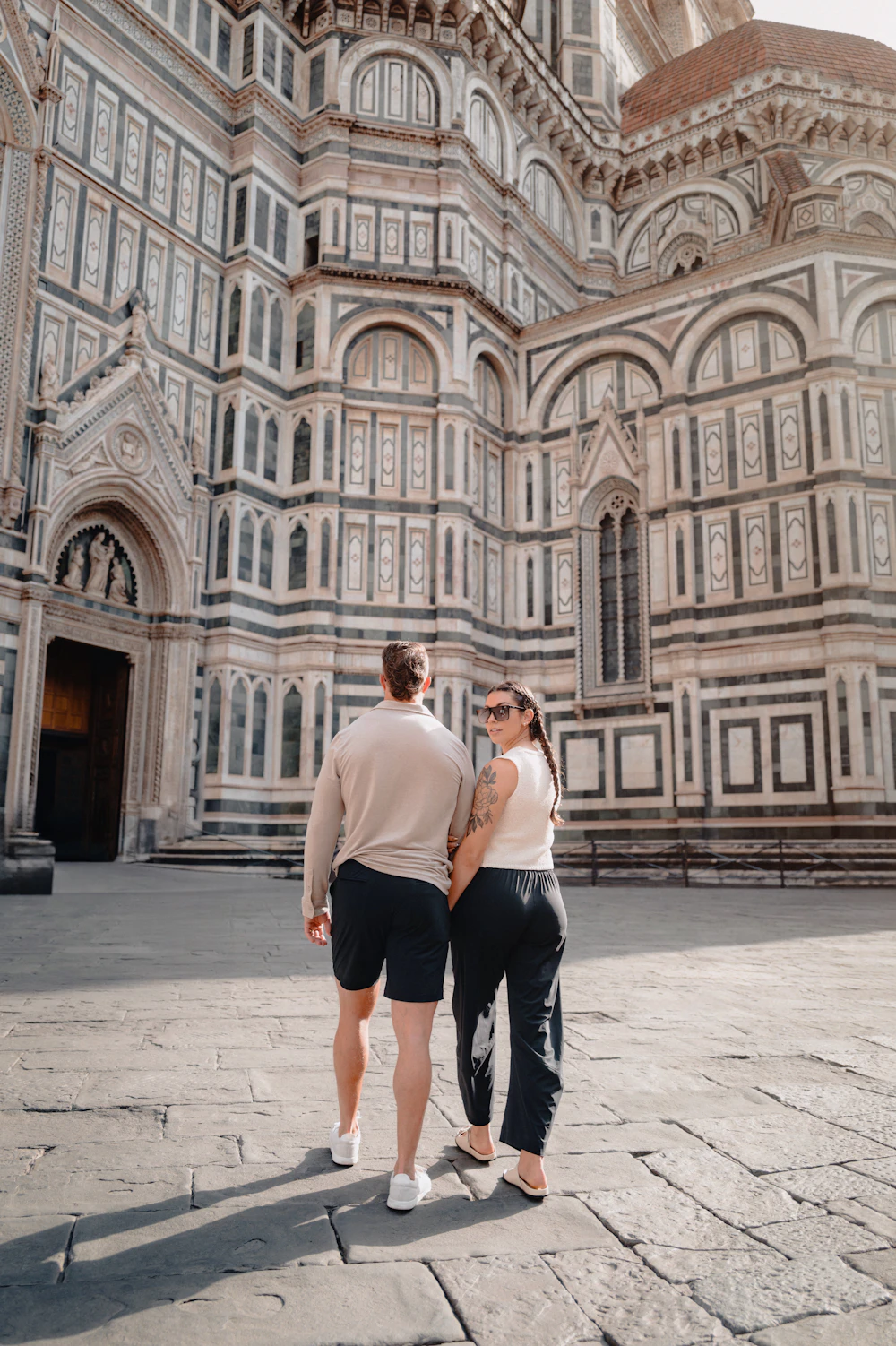 Sofia and James holding hands in front of the cathedral facade
