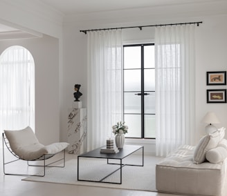 Modern living room with minimalist furniture and white curtains.