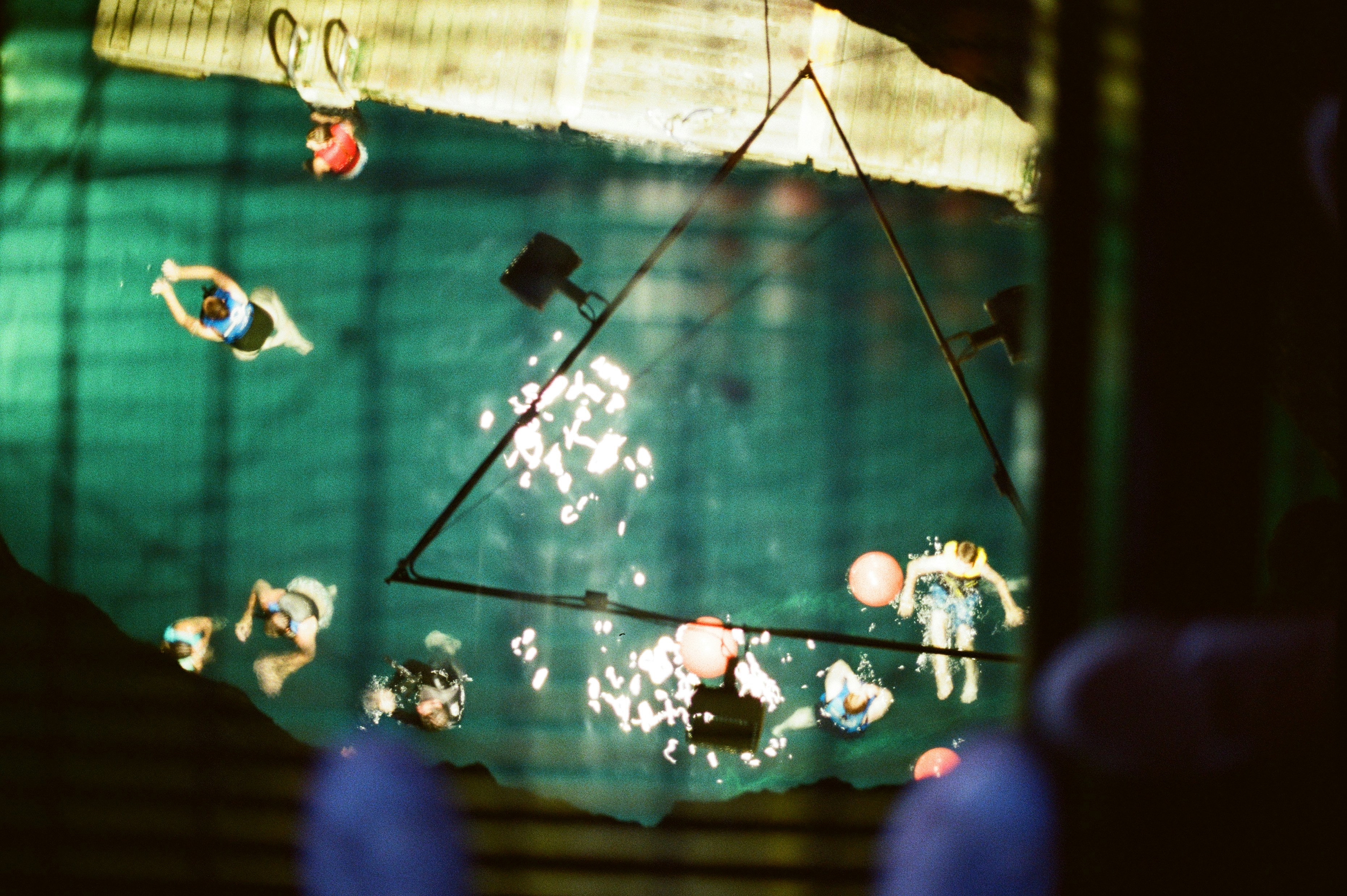 People swimming in a pool with a triangular structure.
