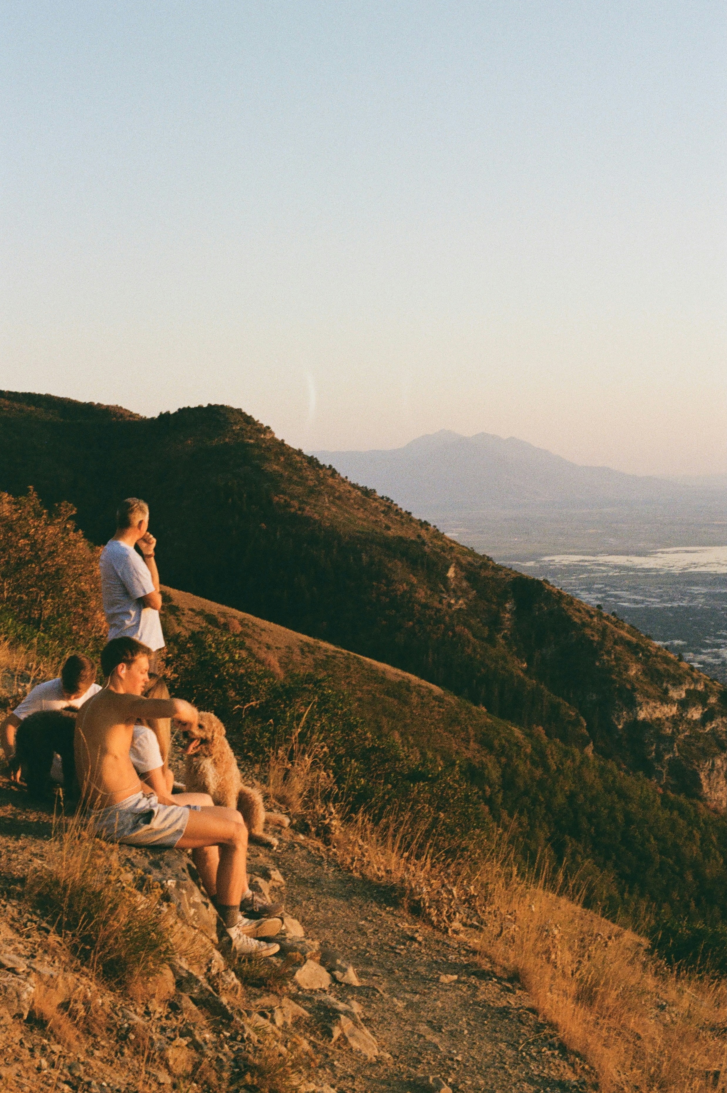 People resting on a mountain overlook at sunset