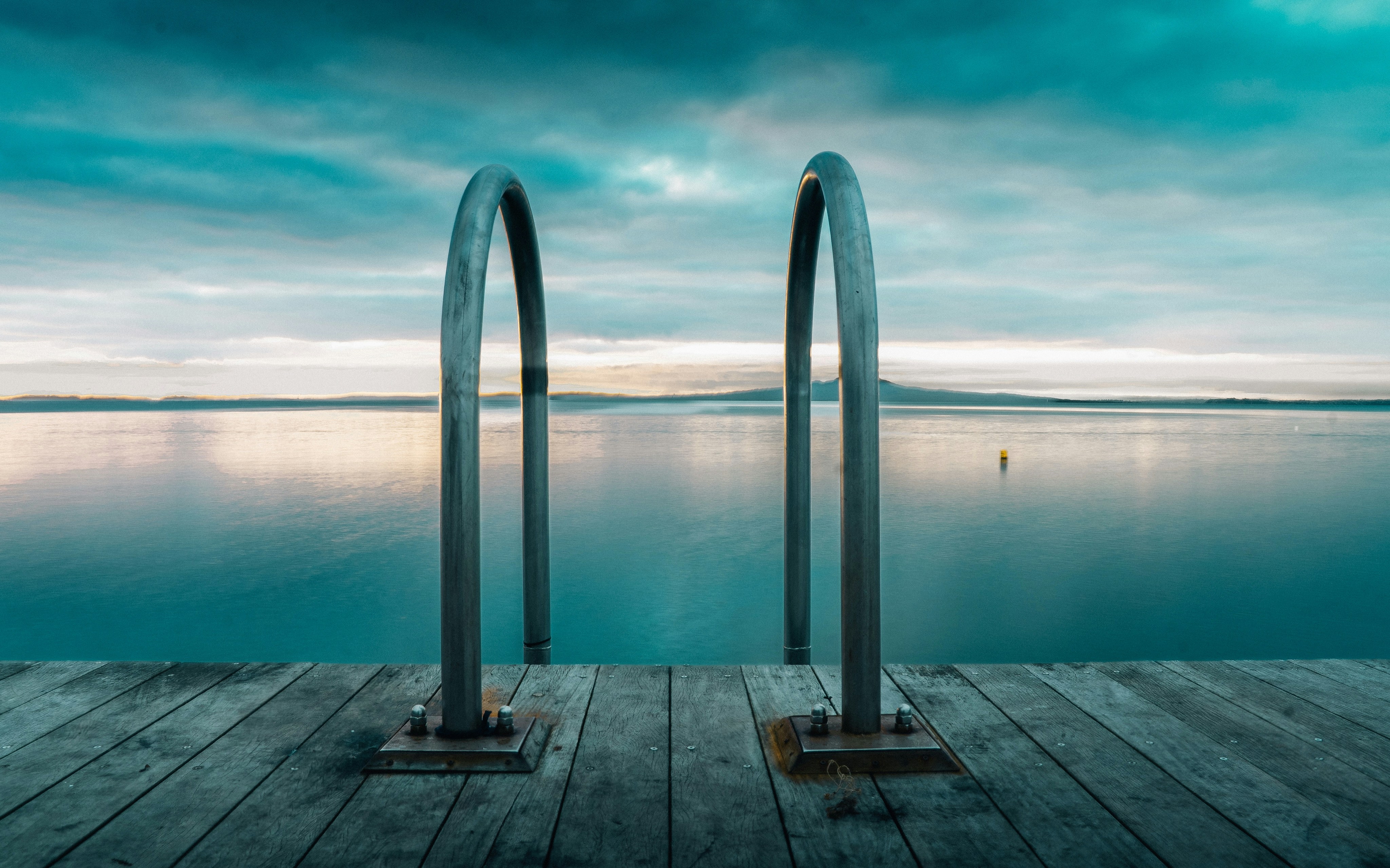 Metal ladder on wooden dock overlooking calm water