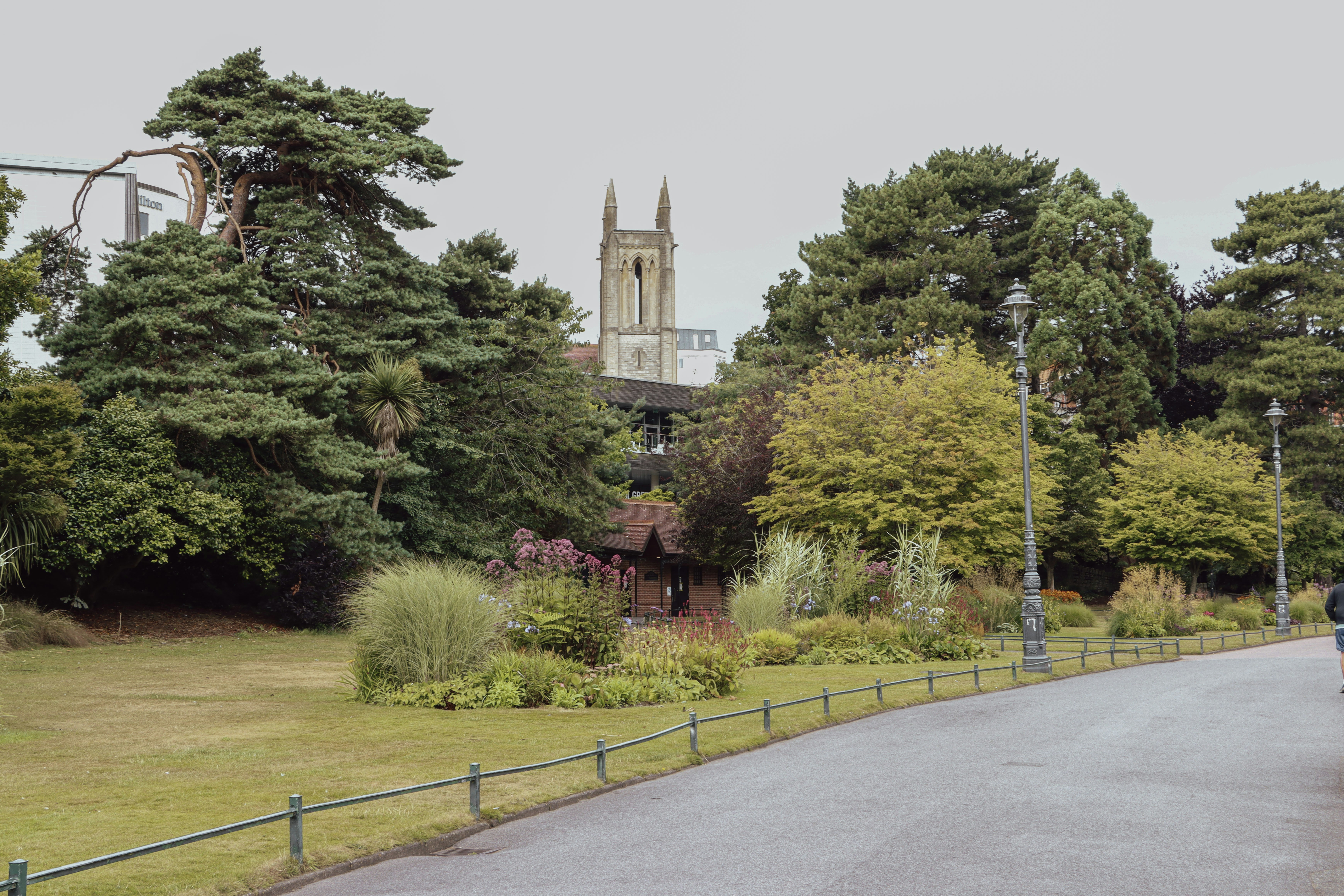 Park path with trees and a distant church tower.