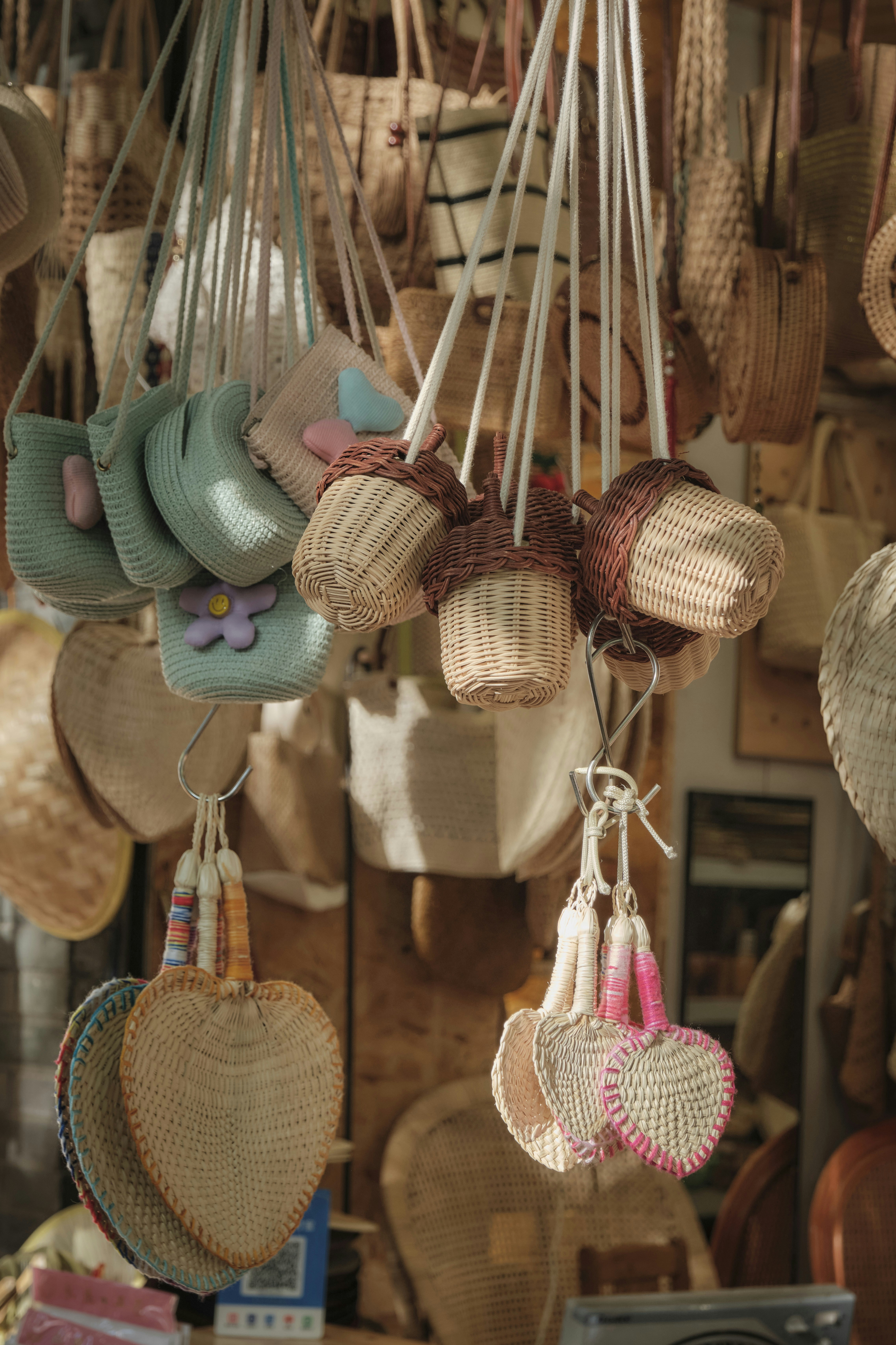 Woven bags and heart-shaped fans hanging at a market.